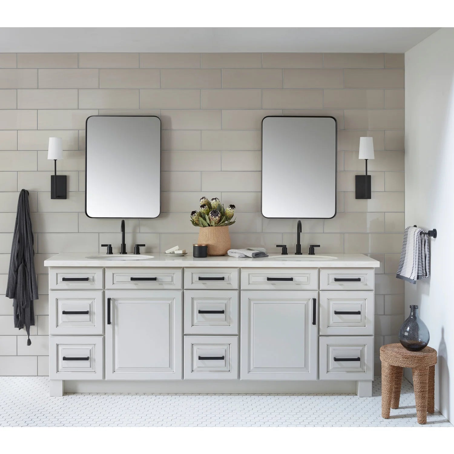 Matte black widespread bathroom faucet on white vanity countertop with two mirrors