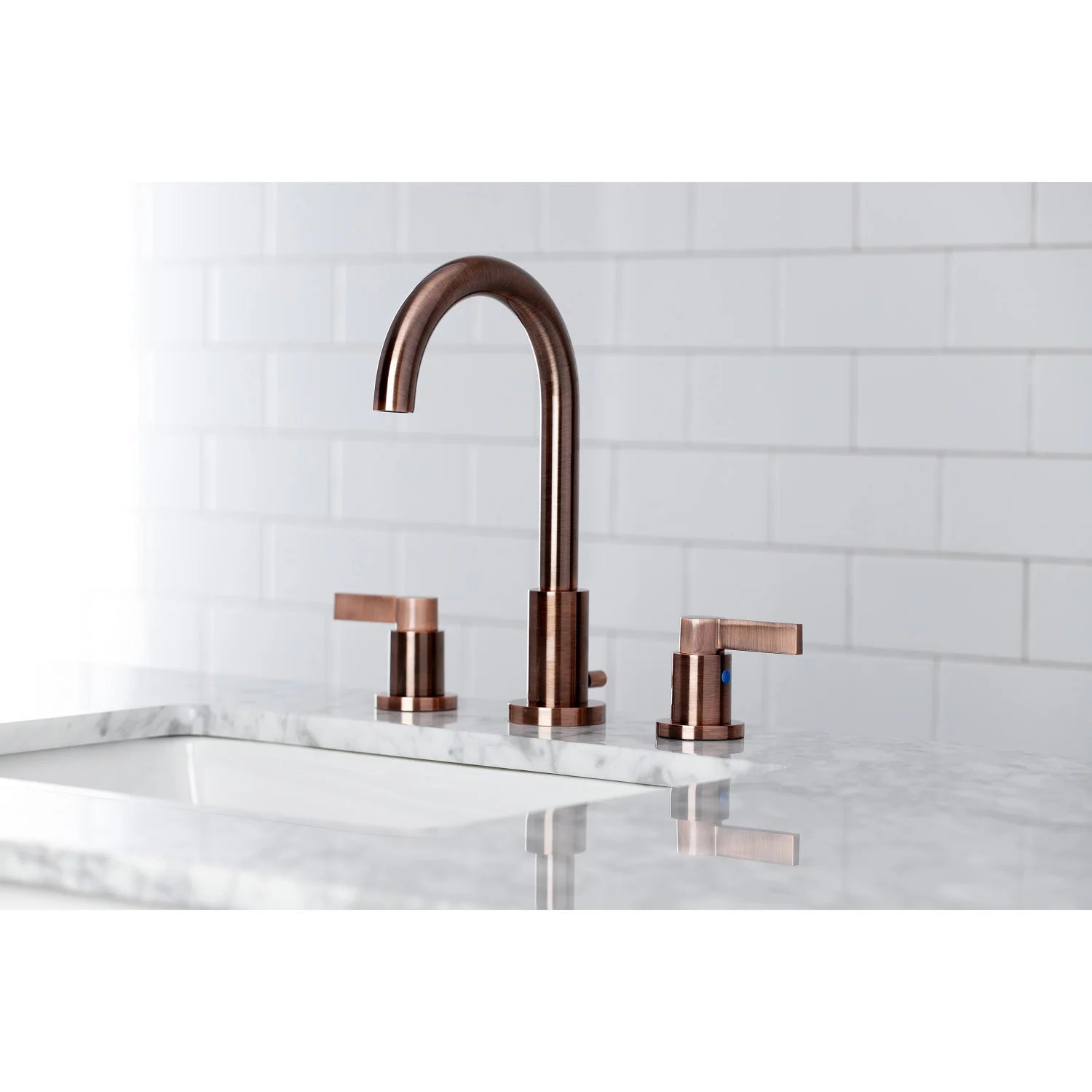 Antique copper widespread bathroom faucet over a sink with curved spout and knobs