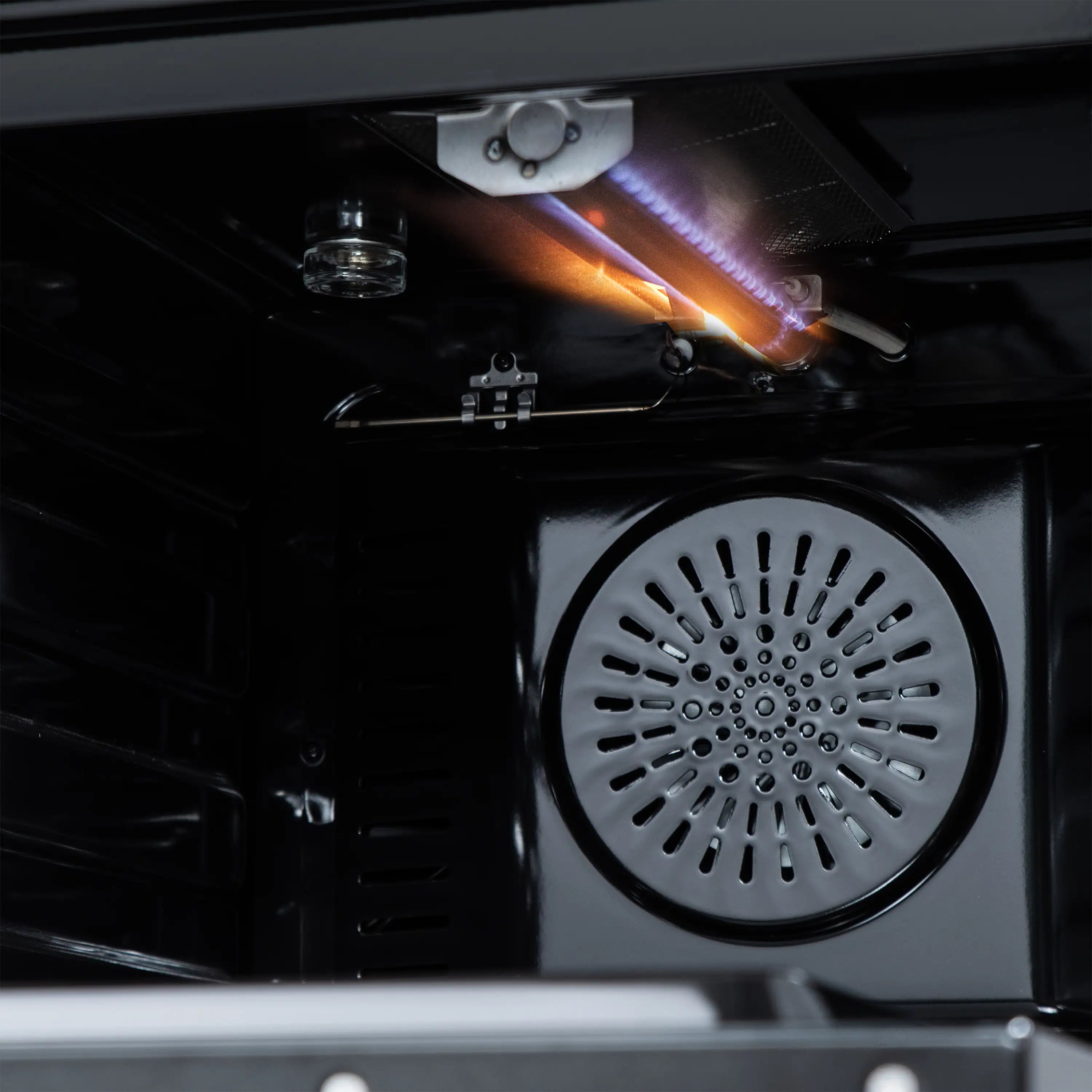 Black oven with visible flame and convection fan vent inside the cooking chamber