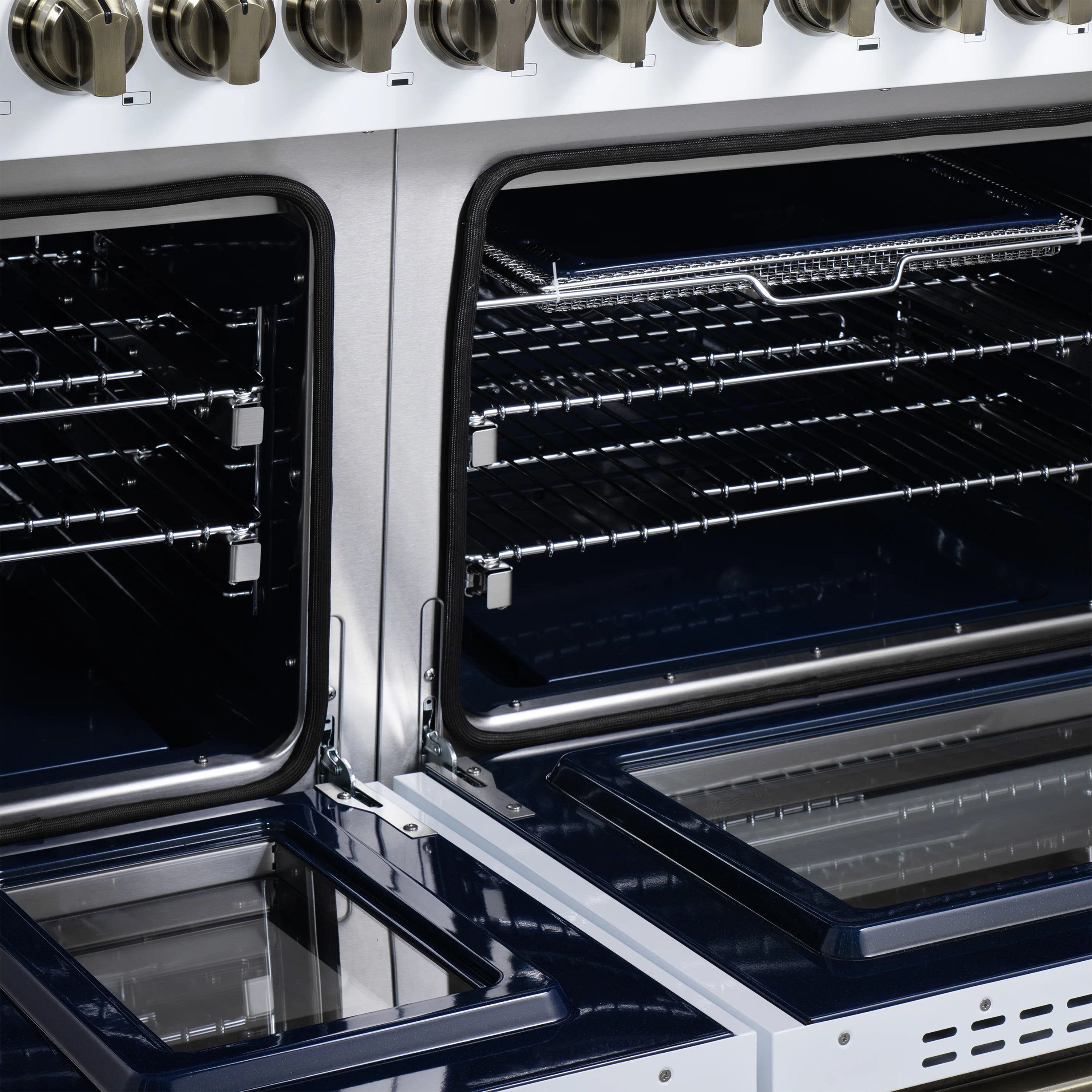 Close-up of open oven compartments with racks, heating elements, and black enamel oven bottoms