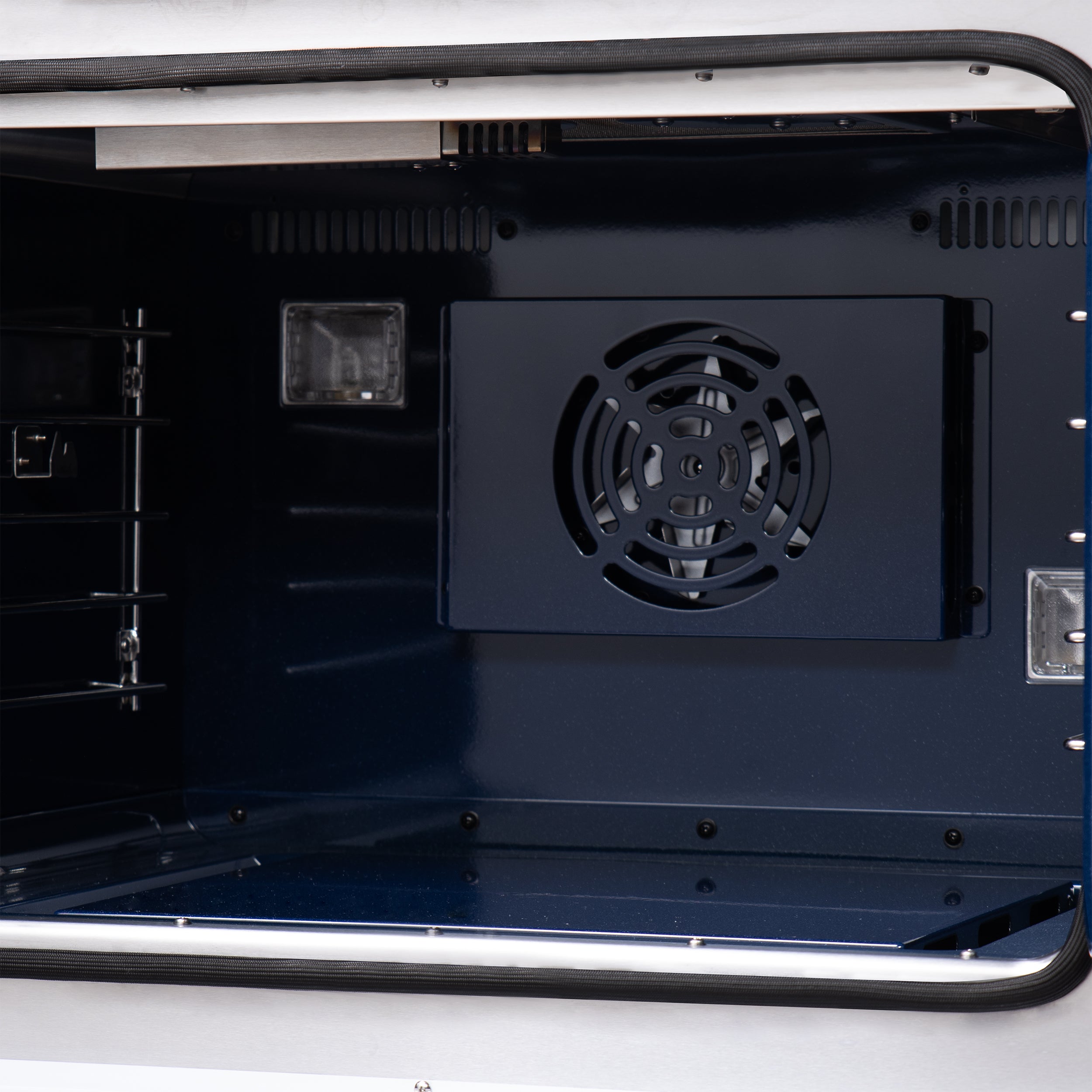 Open oven cavity of black gas range with convection fan vent and side lighting