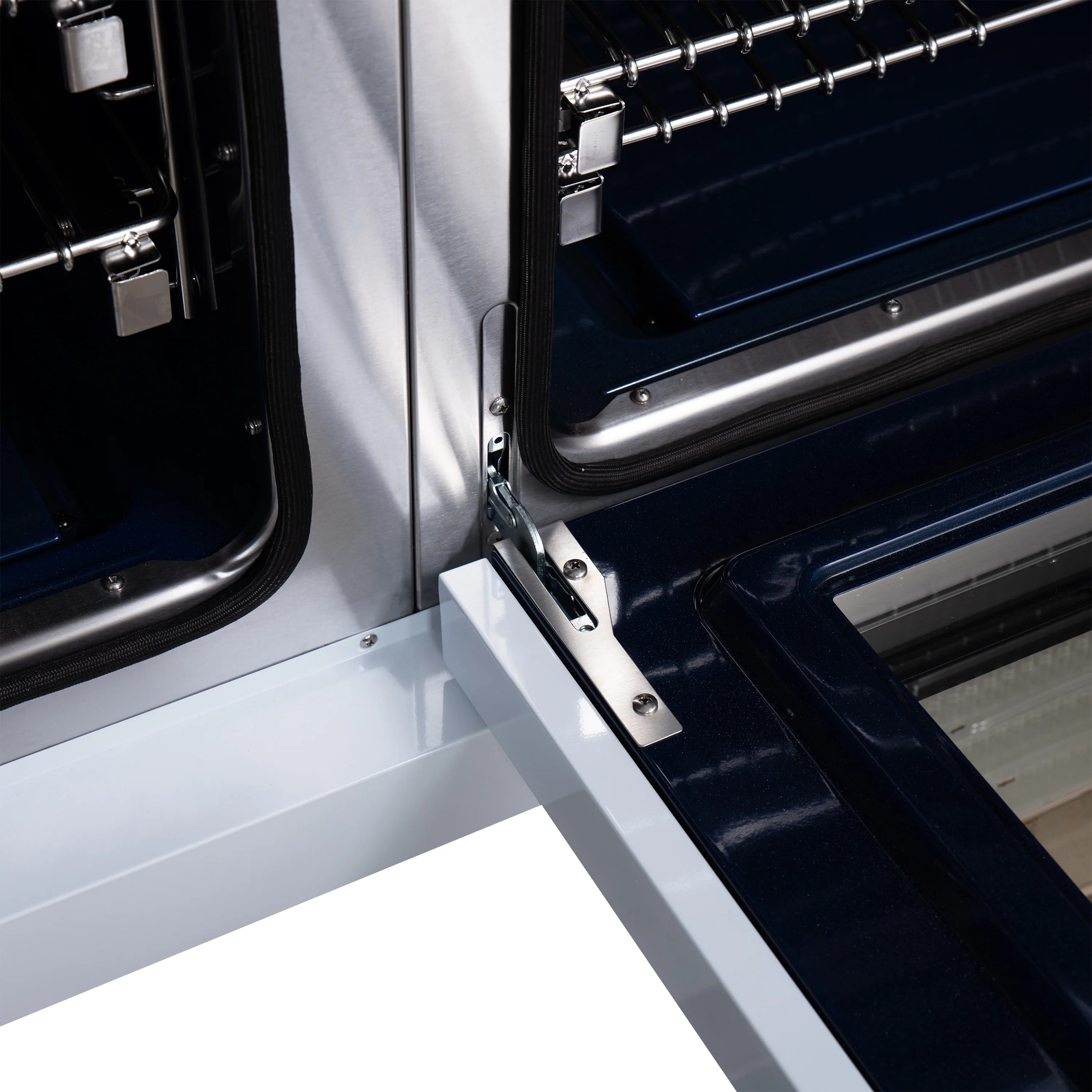 Close-up of French oven door, antique brass handle, and black oven interior.