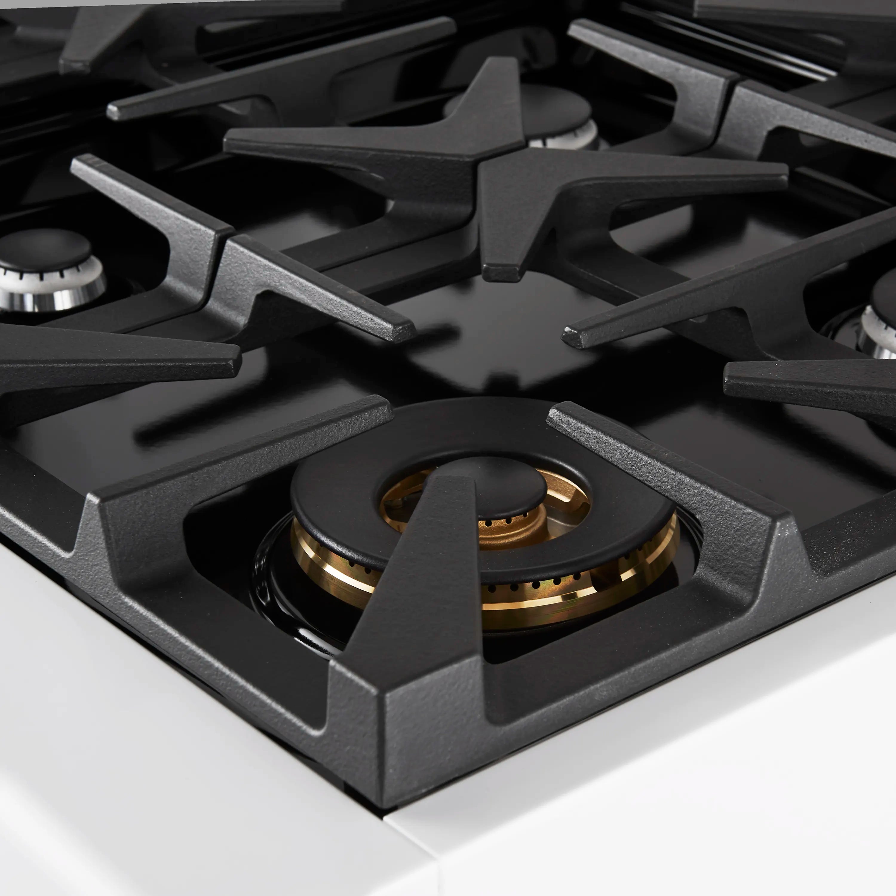 Gas range burner with black grates and brass-colored burner ring in center