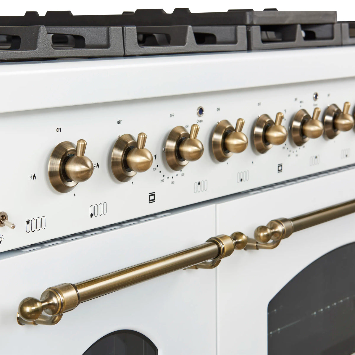 White gas range control panel with antique-brass knobs and front brass bar handle