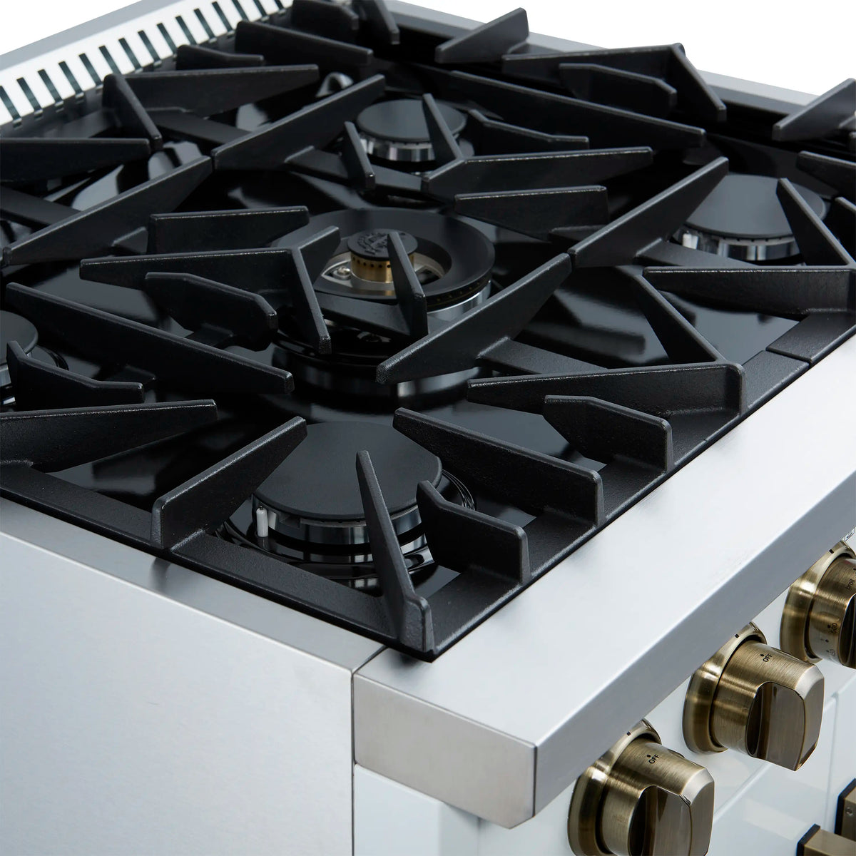 Black gas burners on a white cooktop with brass control knobs