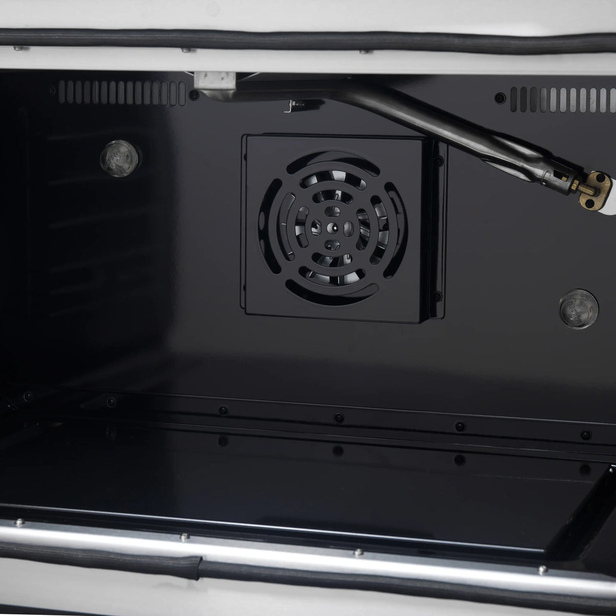 Black oven cavity wall vent with circular fan grille and connected tubing