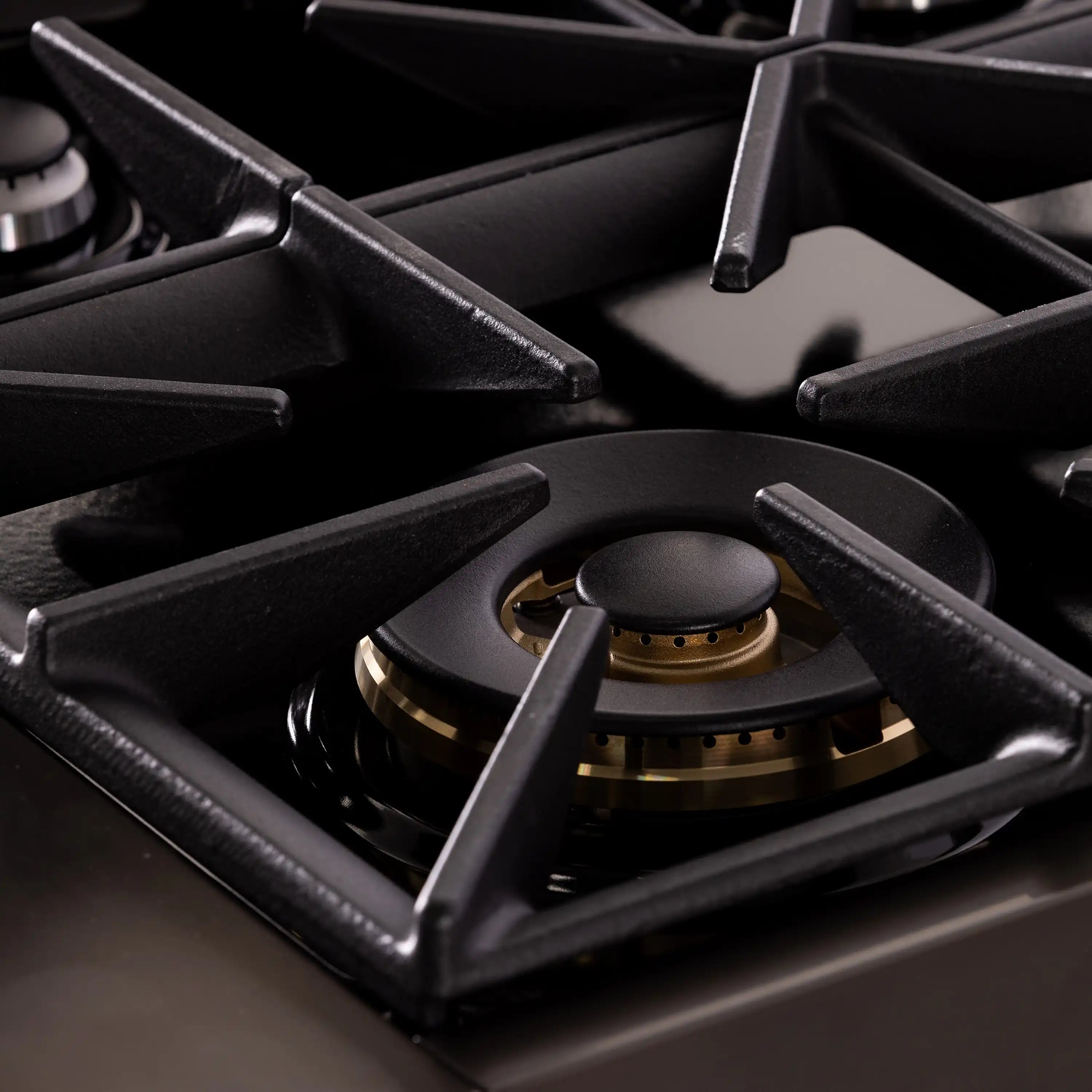 Single gas burner with black cast grates and gold ring on dark titanium range top