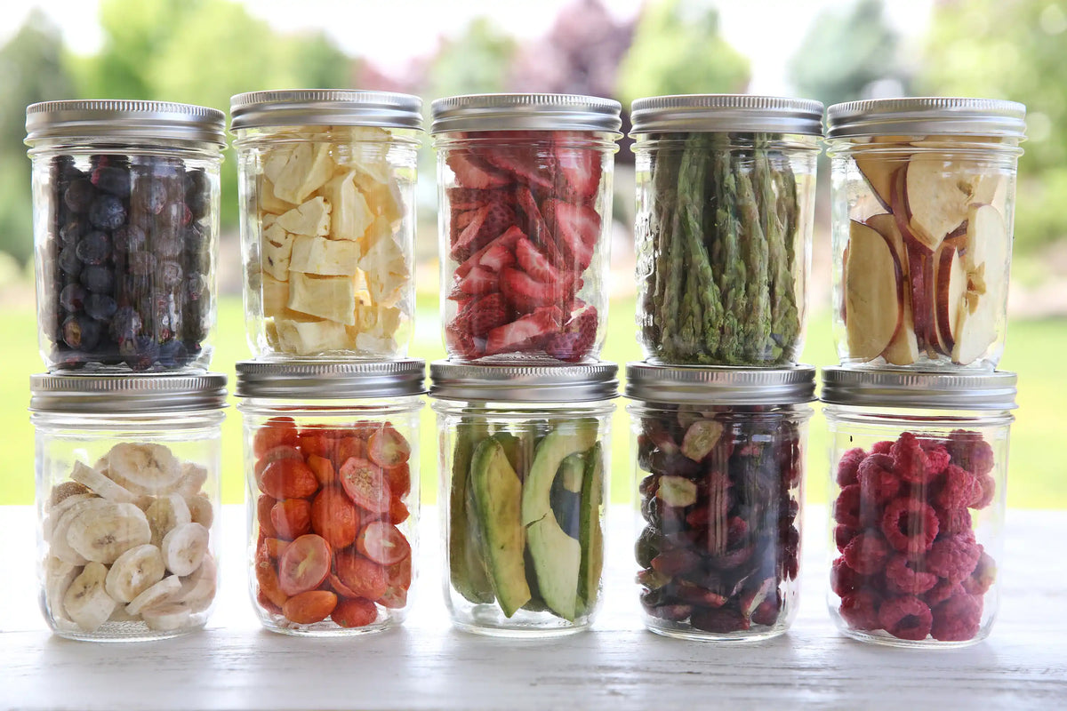 Assorted freeze-dried foods in clear glass jars with metal lids, variety display