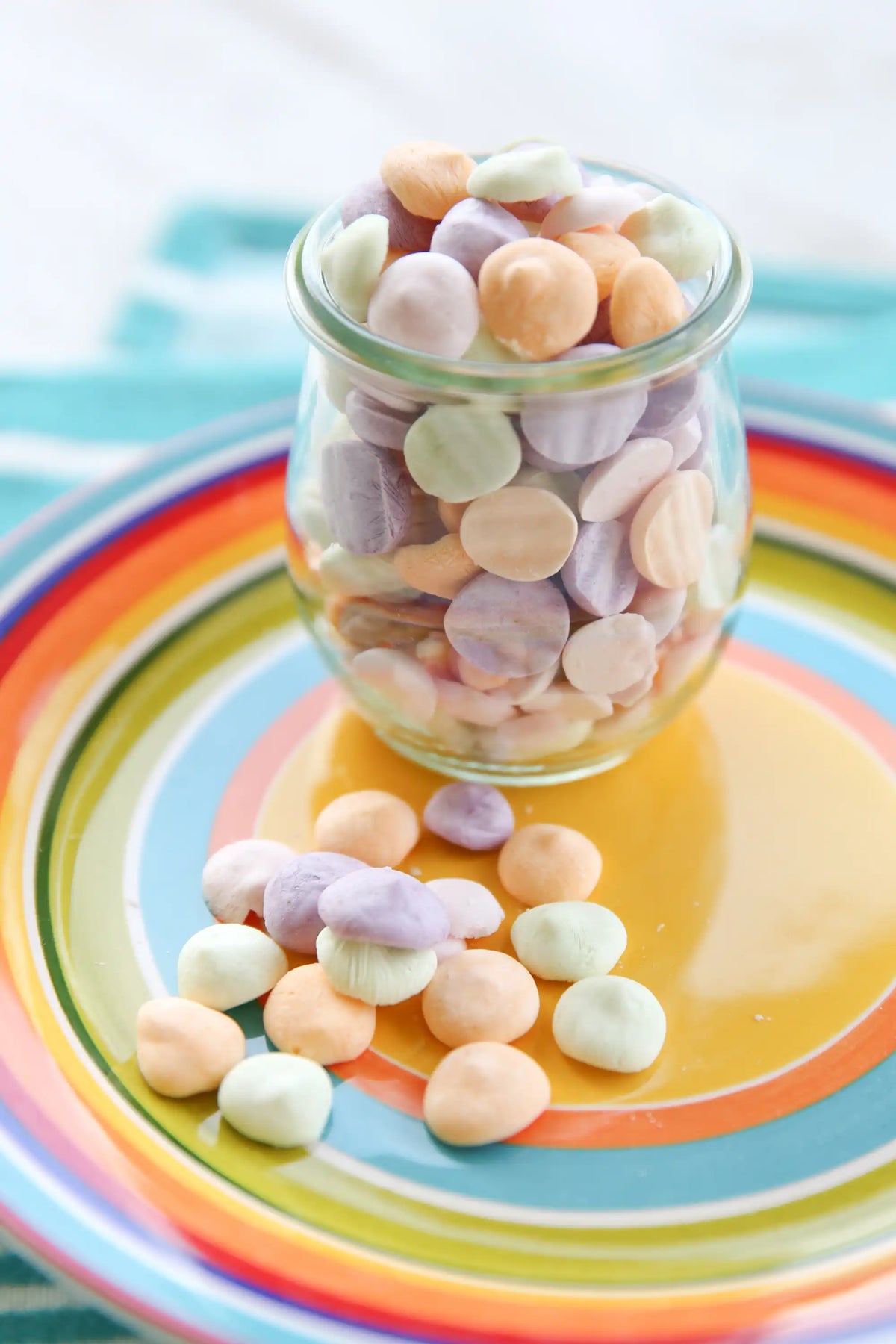 Clear glass jar of freeze-dried marshmallow-like pieces on colorful plate