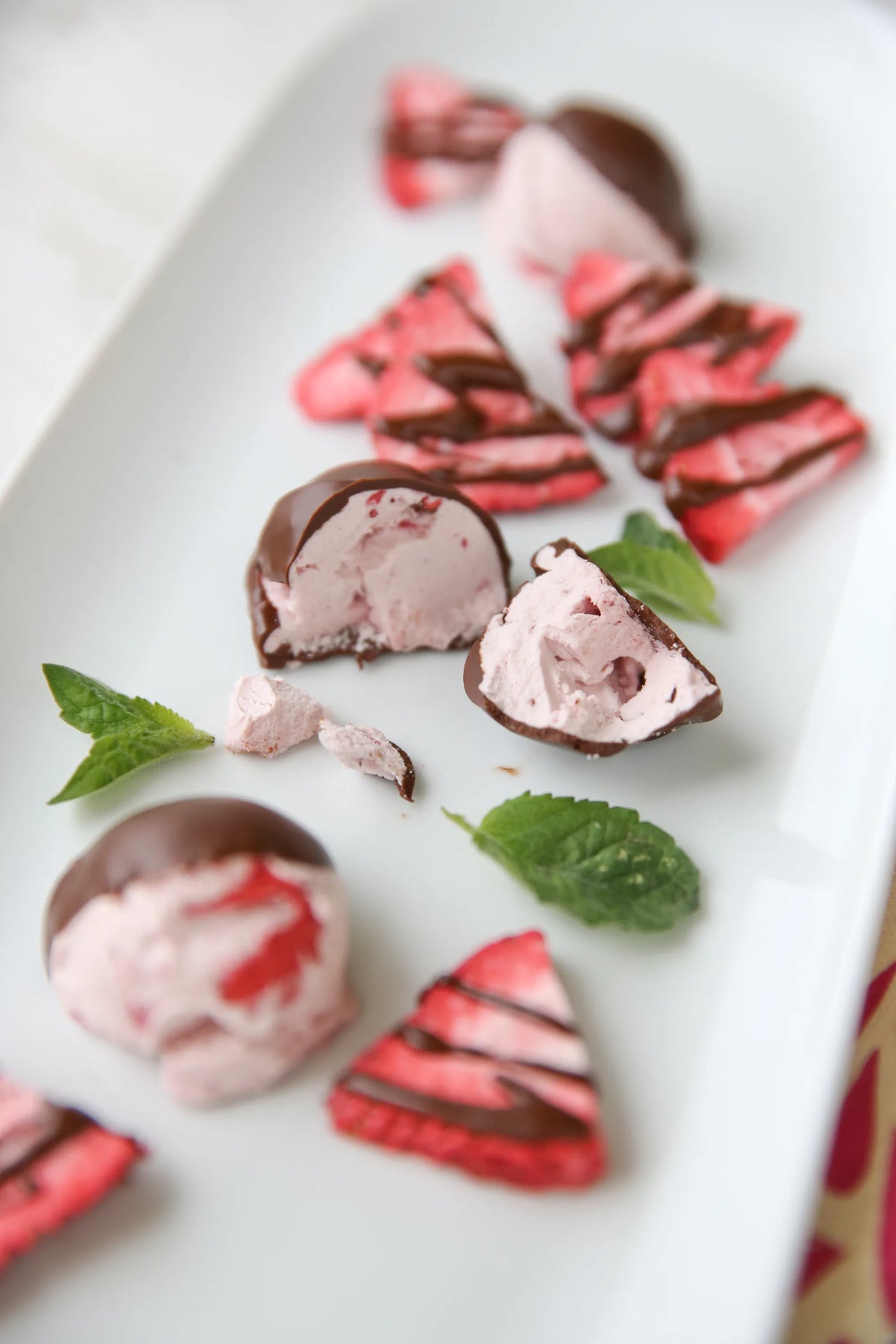 Freeze-dried dessert chunks and crackers on a plate with green herb leaves