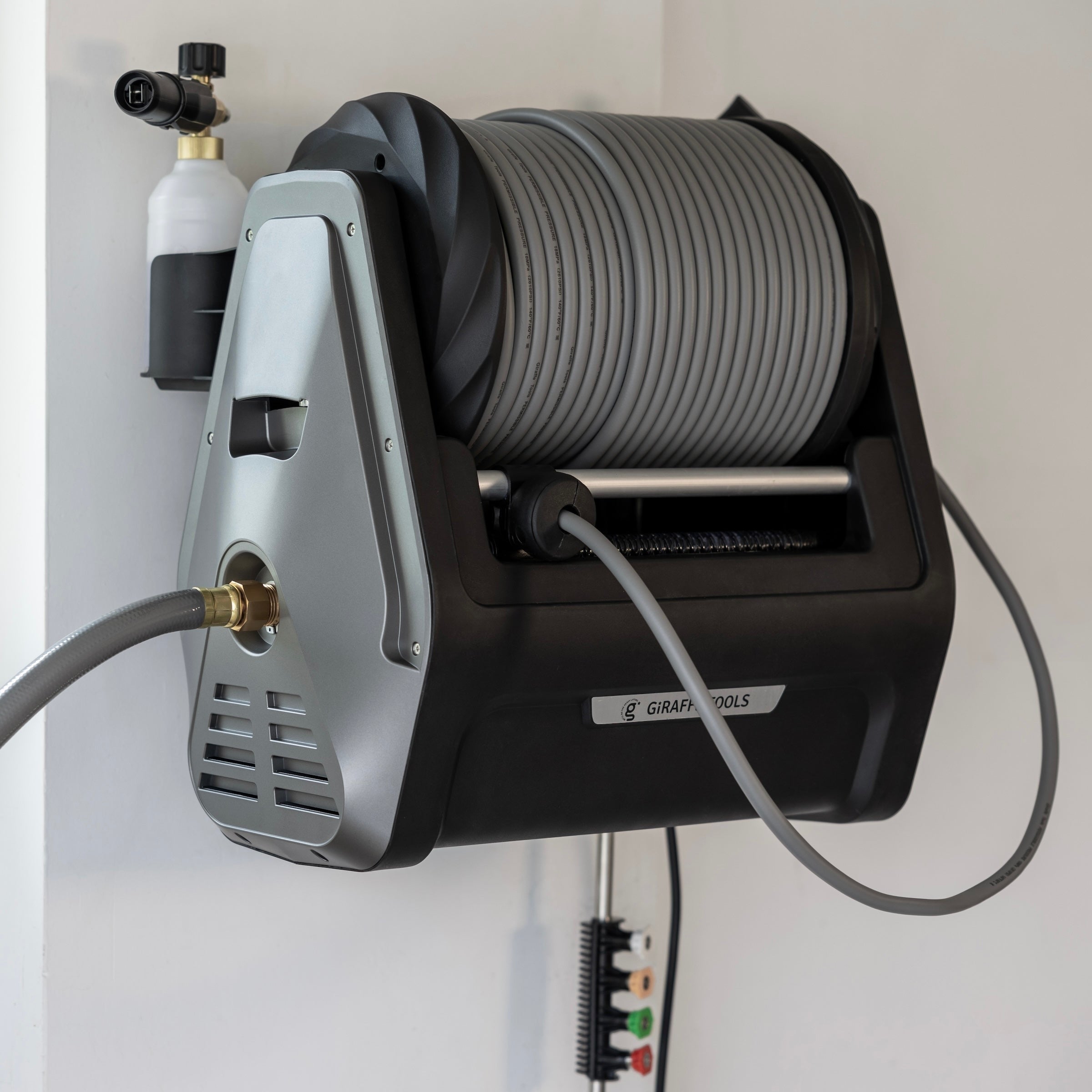 Retractable pressure washer with gray housing and coiled hose on wall bracket