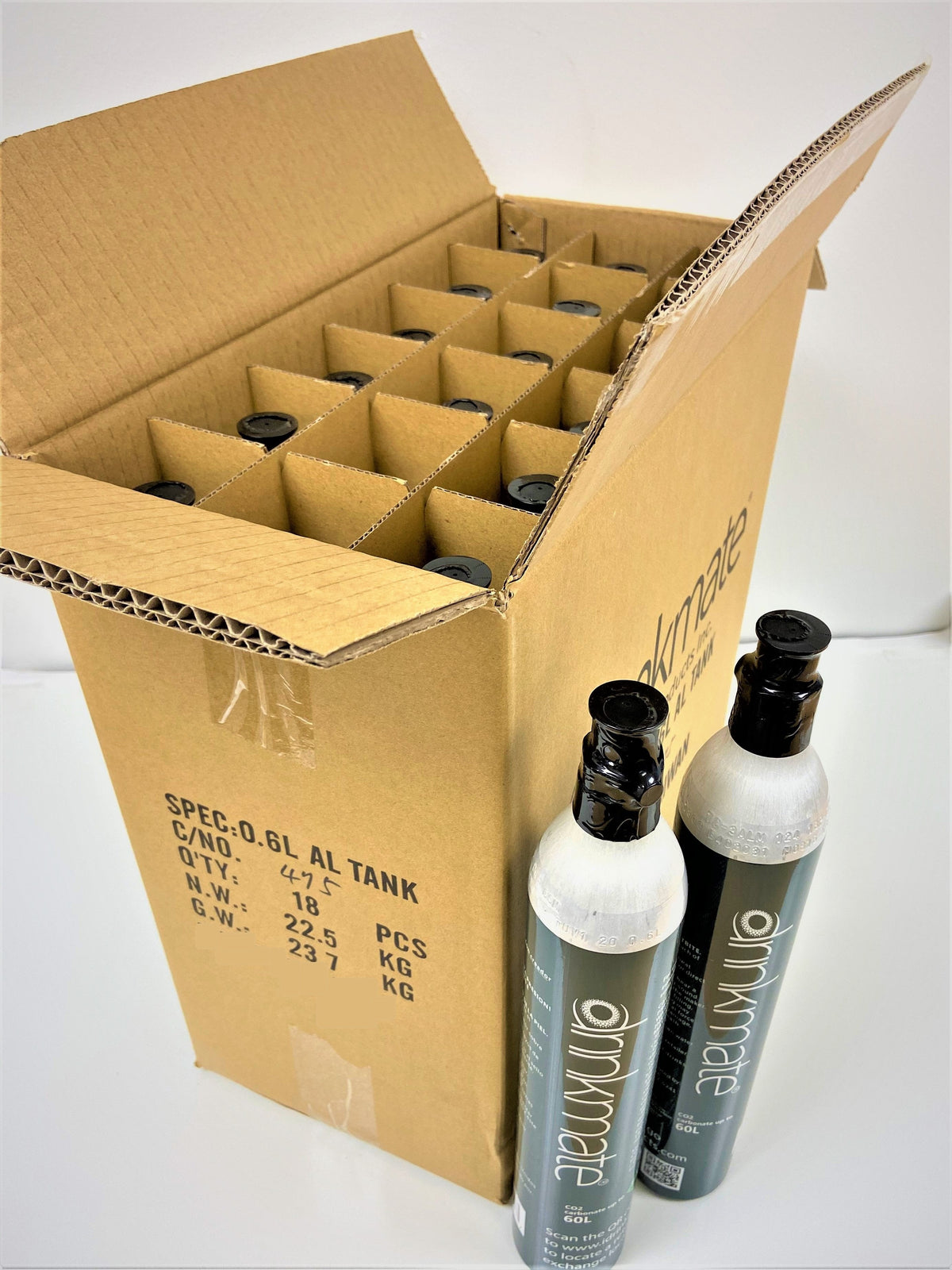 Open cardboard carton of Drinkmate CO2 cylinders, showing several dark bottles