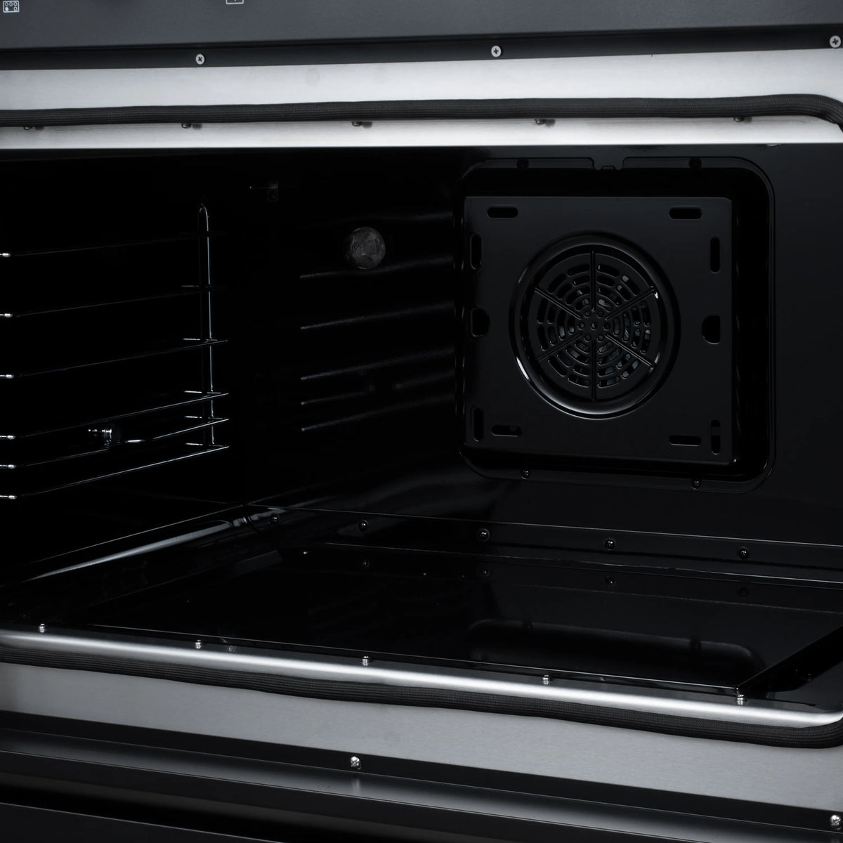 Black oven interior with racks and rear convection fan housing opening