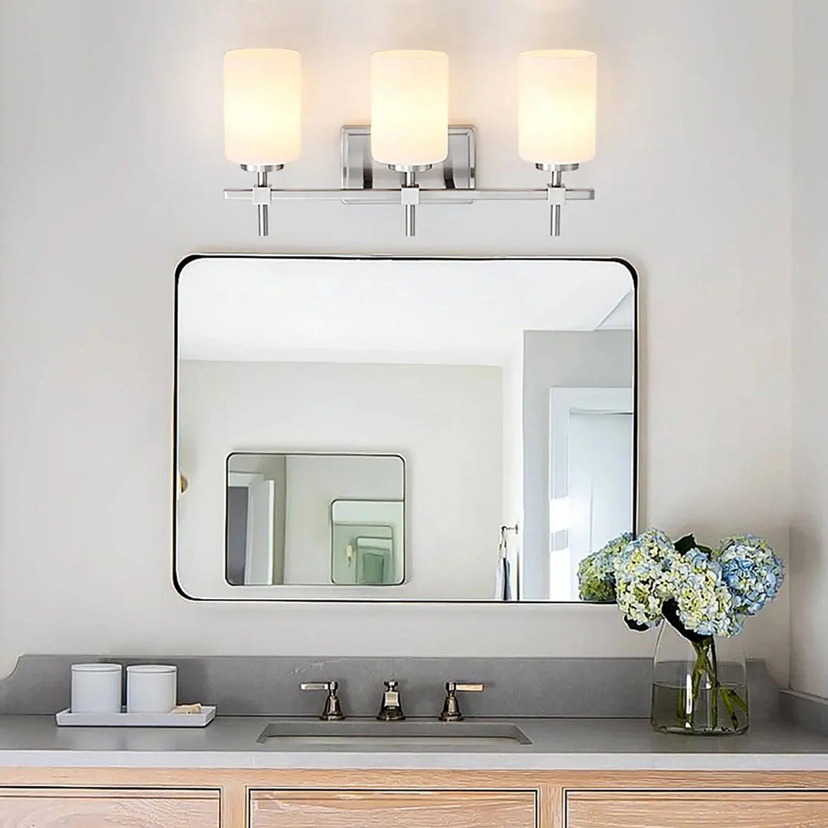 3-light bathroom vanity light with three frosted glass lamp shades on a brushed metal frame