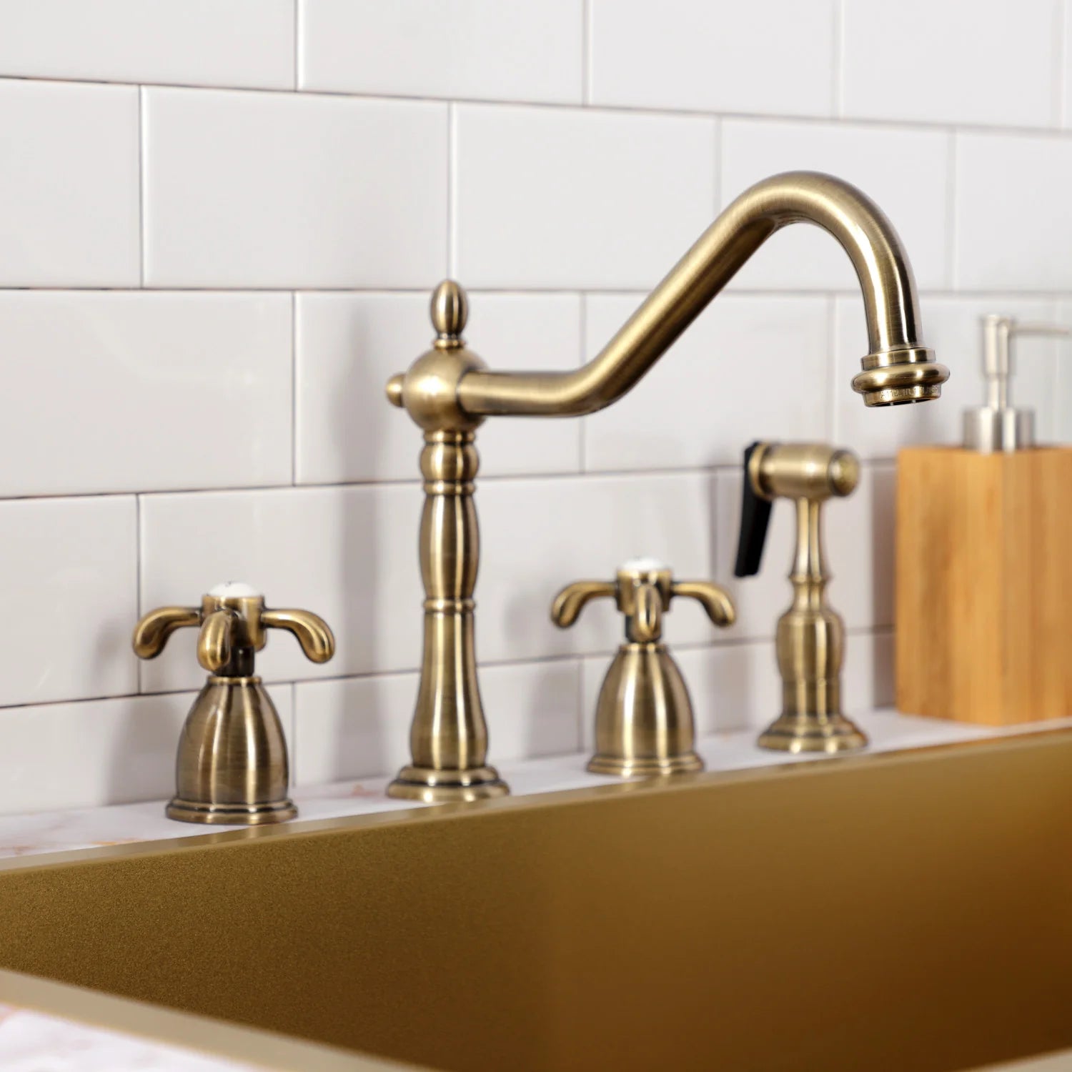 Antique brass widespread kitchen faucet with gooseneck spout, sprayer, and two handles