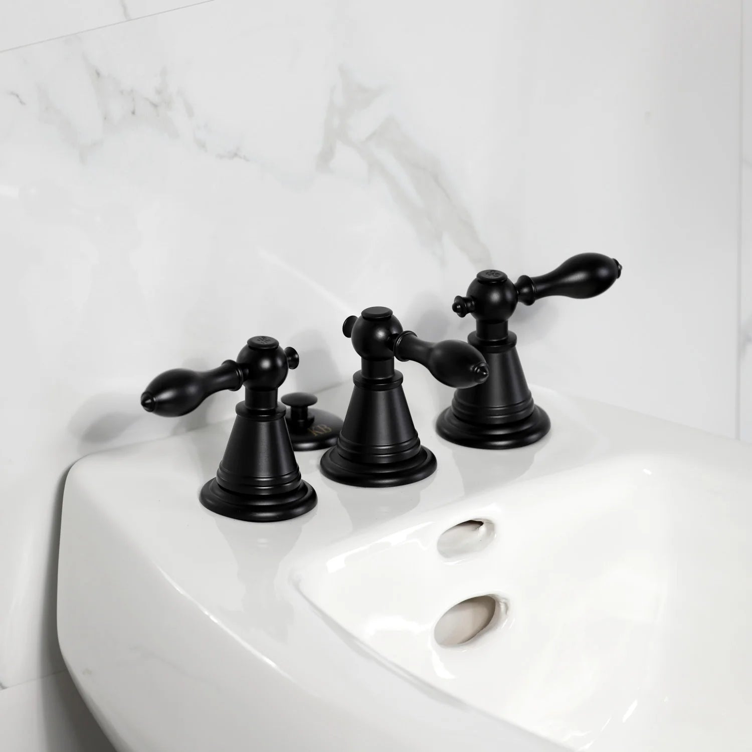 Matte black three-handle bidet faucet set mounted on the white fixture deck