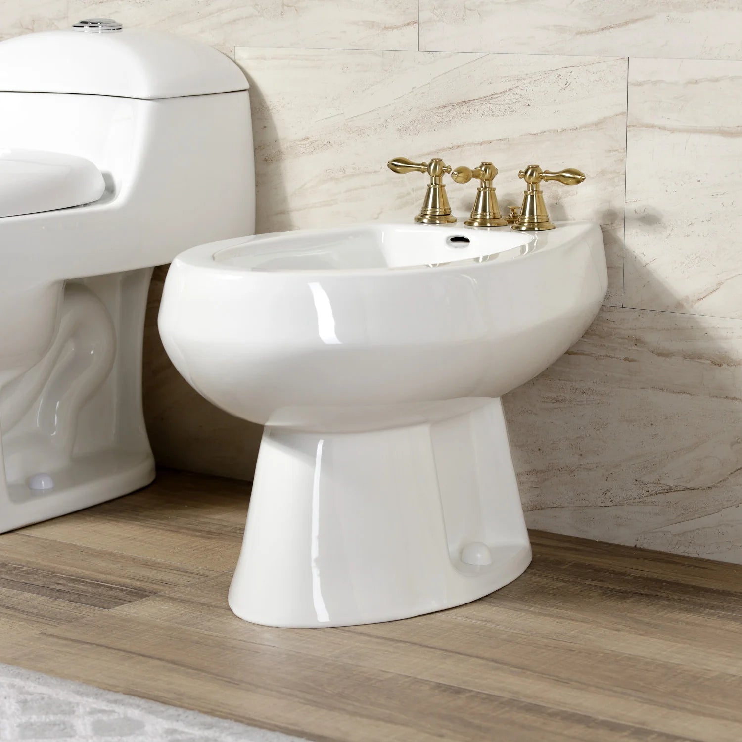 Victorian three-handle bidet faucet with brushed brass handles on white bidet