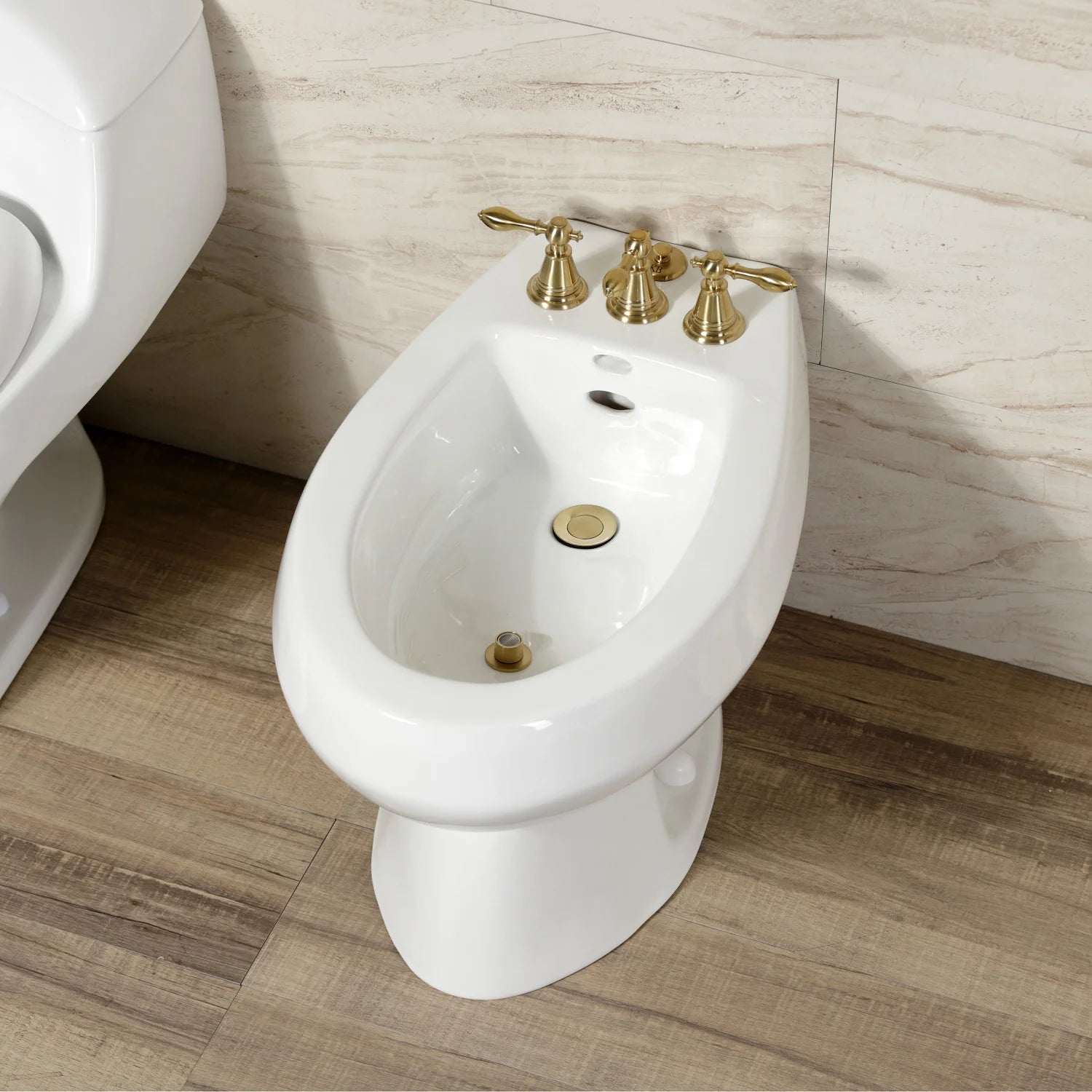Brushed brass three-handle Victorian bidet faucet on white bidet fixture