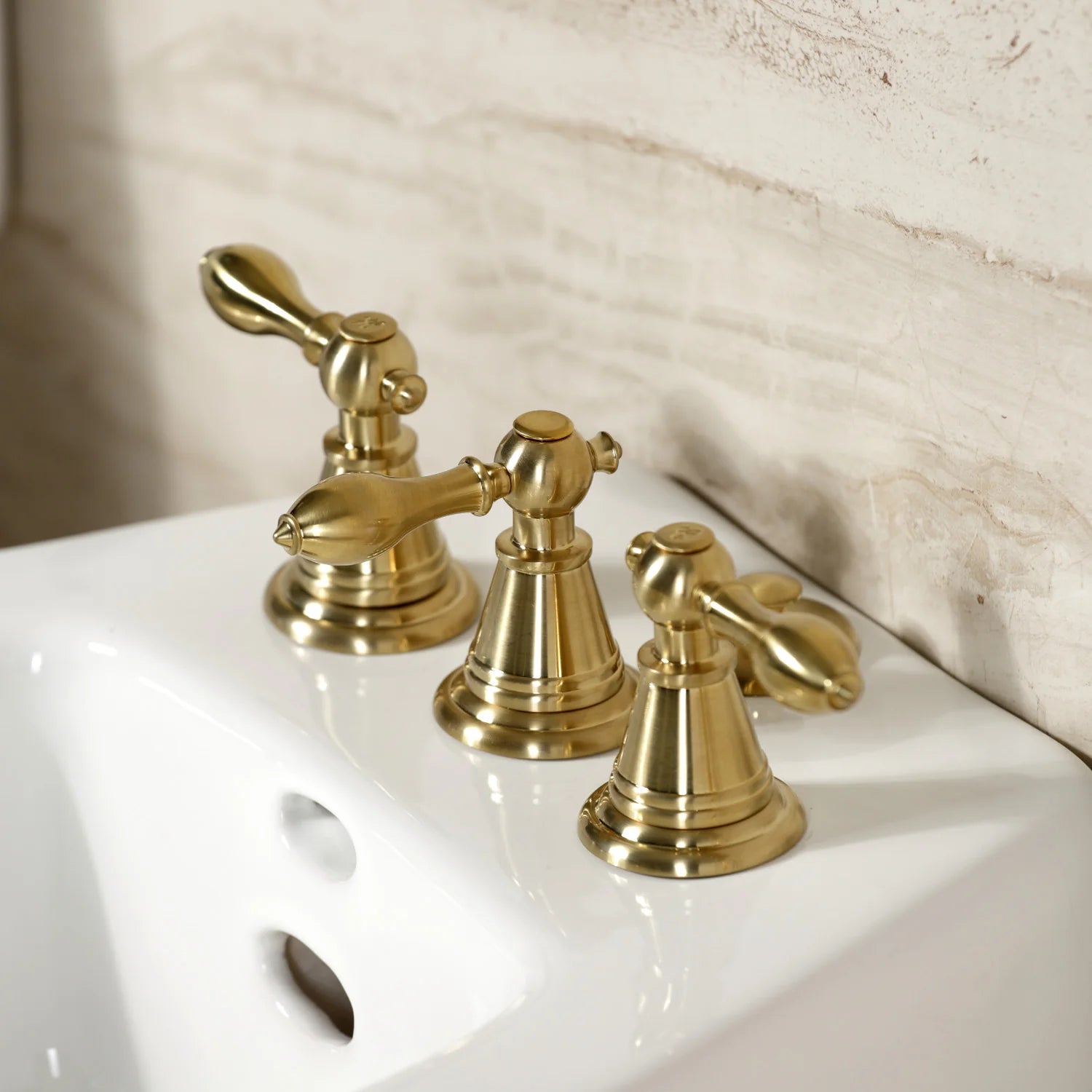 Brushed brass three-handle Victorian bidet faucet on white bidet