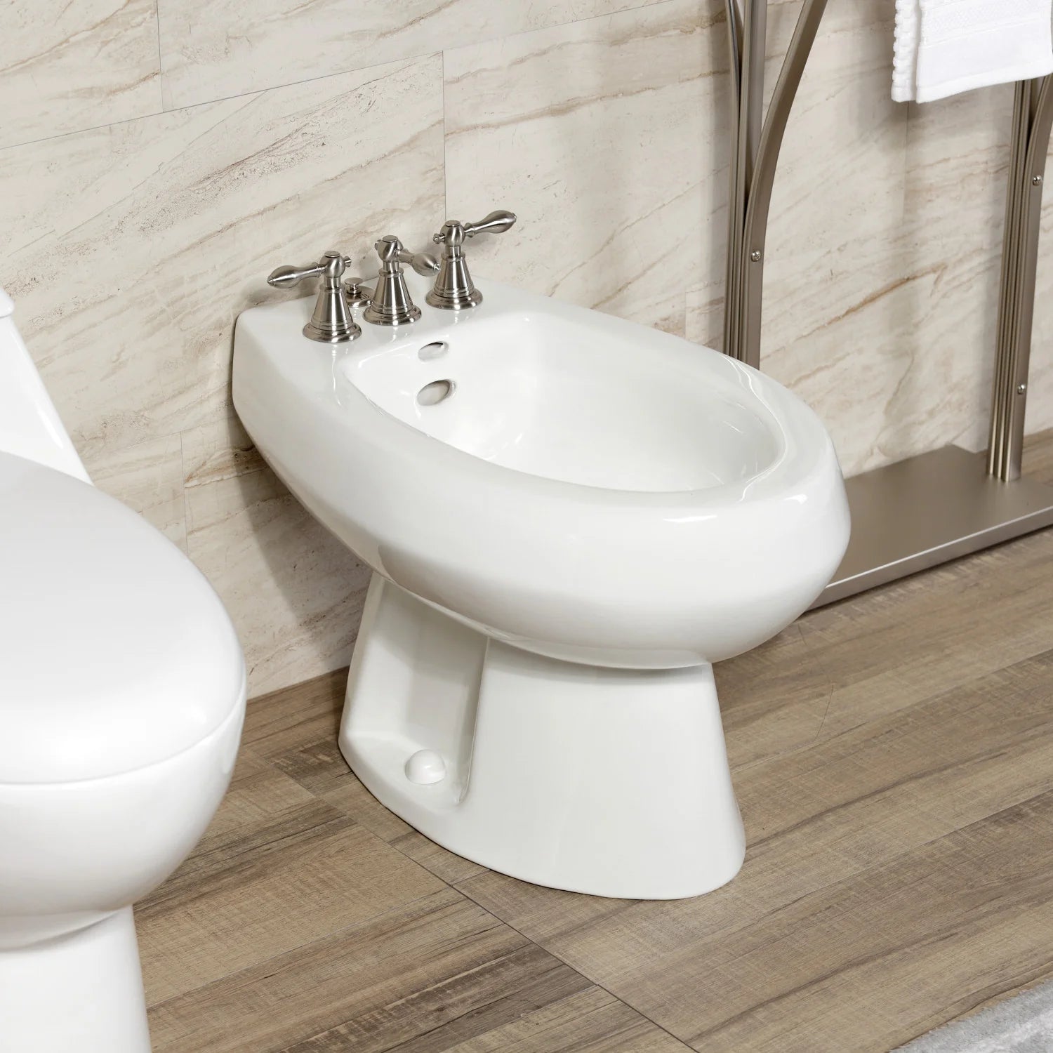 White one-piece bidet with brushed nickel three-handle faucet and spout.