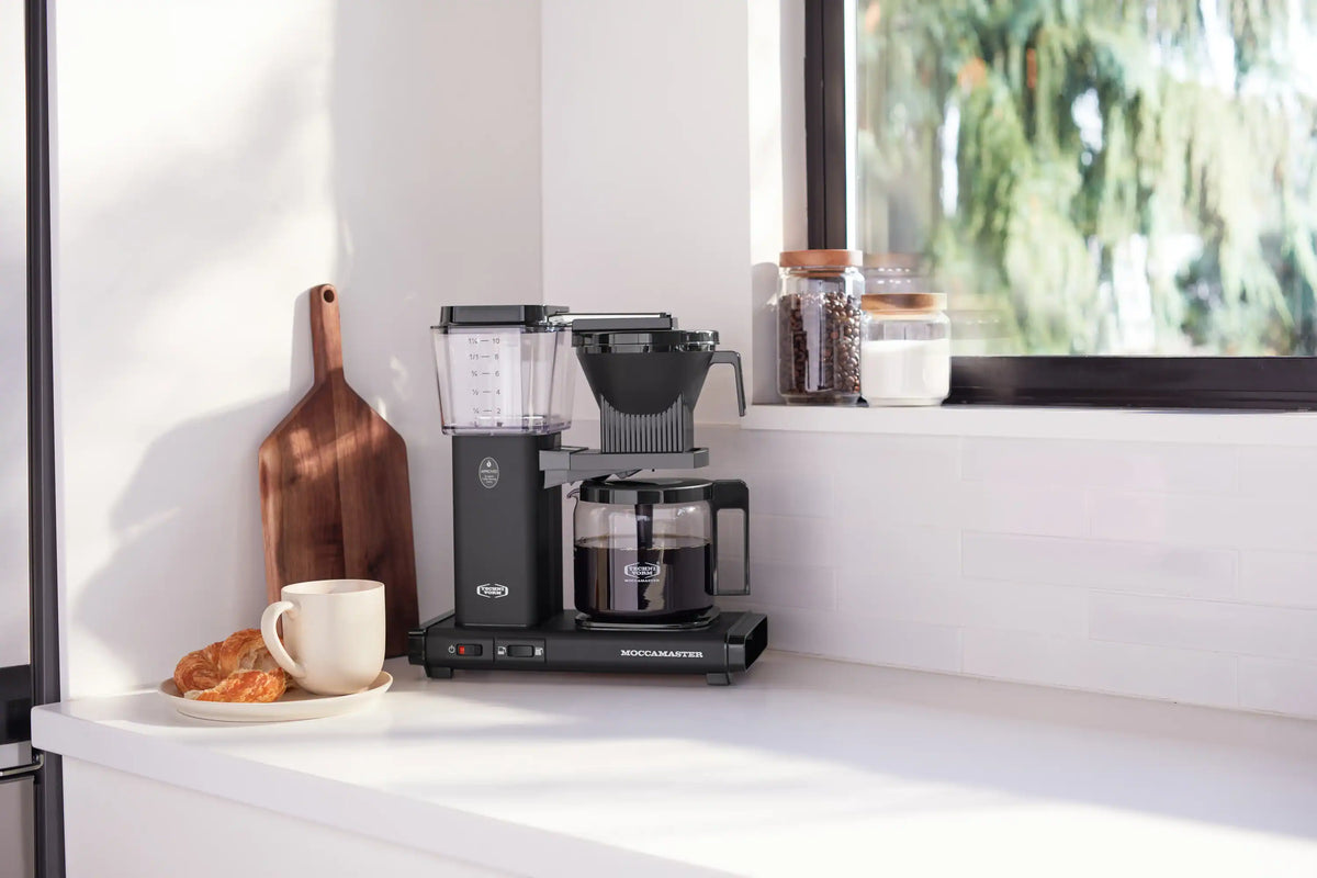 Moccamaster matte black coffee maker with glass carafe, reservoir, and brew head