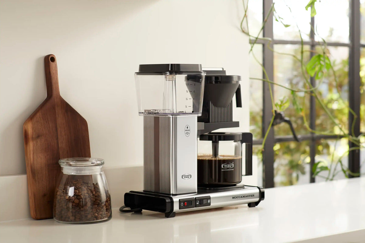 Moccamaster coffee maker with clear glass carafe and black funnel brewer on base.