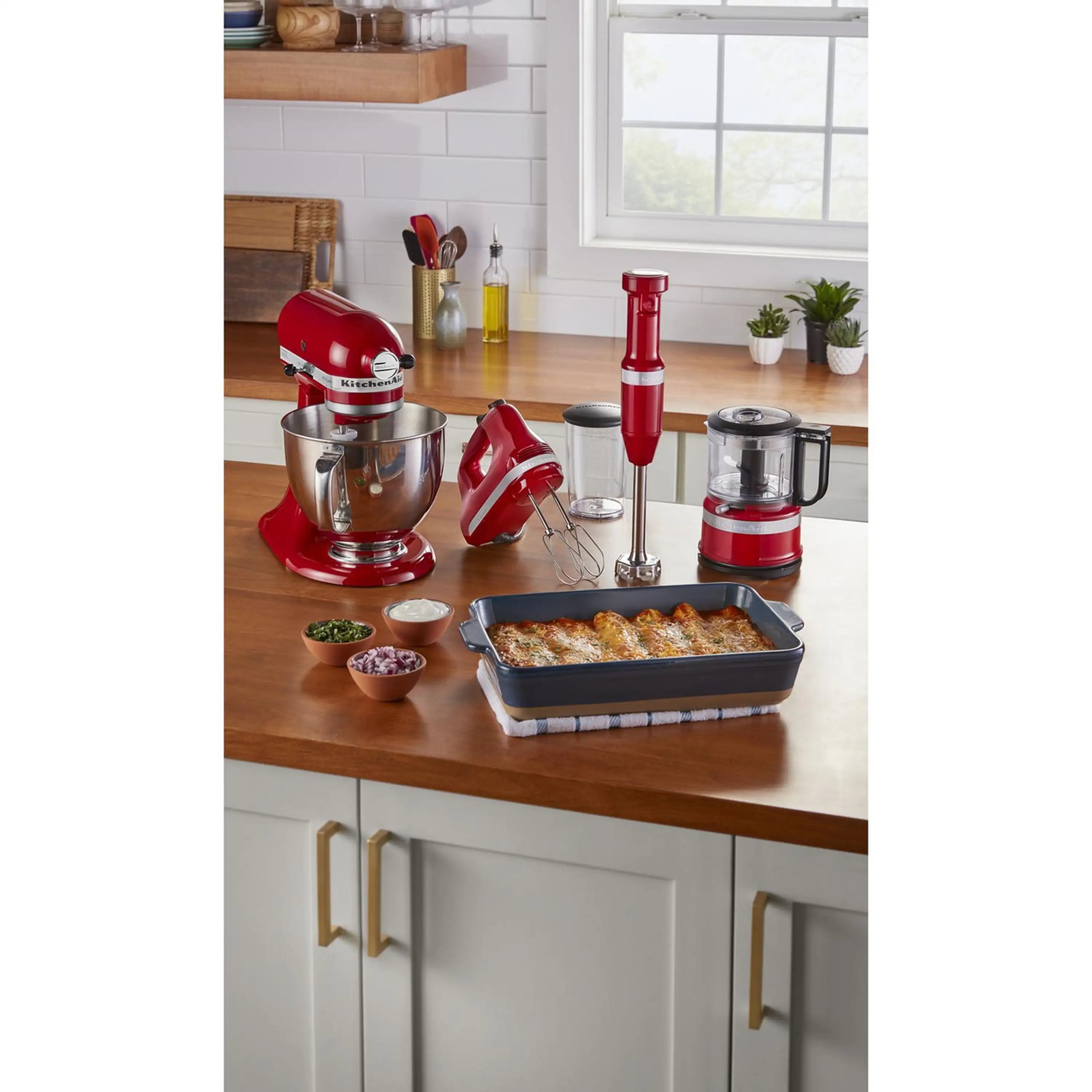 Red KitchenAid hand mixer with beaters beside a stand mixer and small appliances