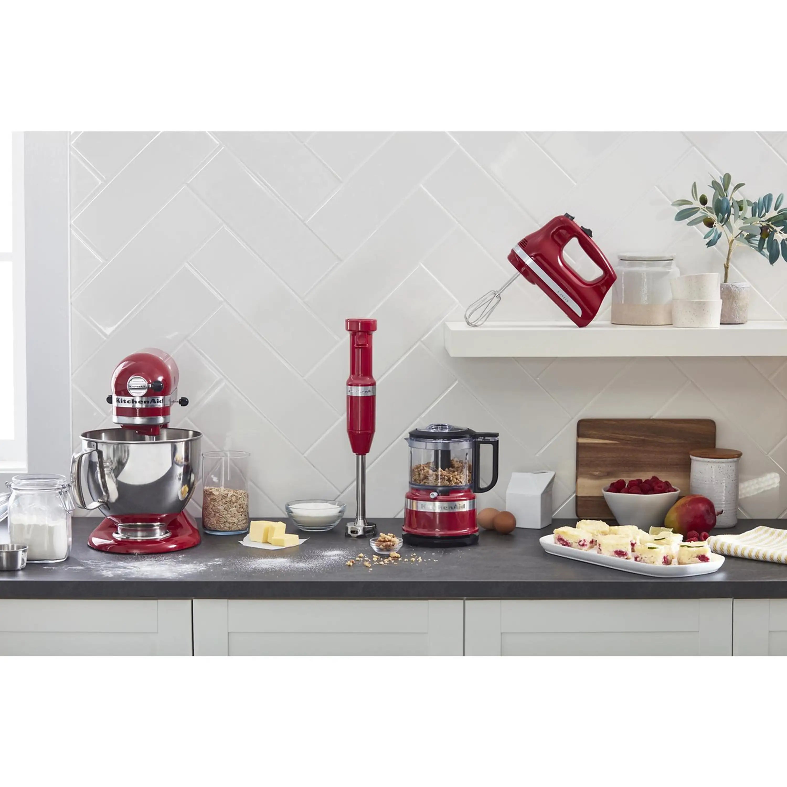 Red KitchenAid hand mixer on countertop with attached beaters, ready to mix