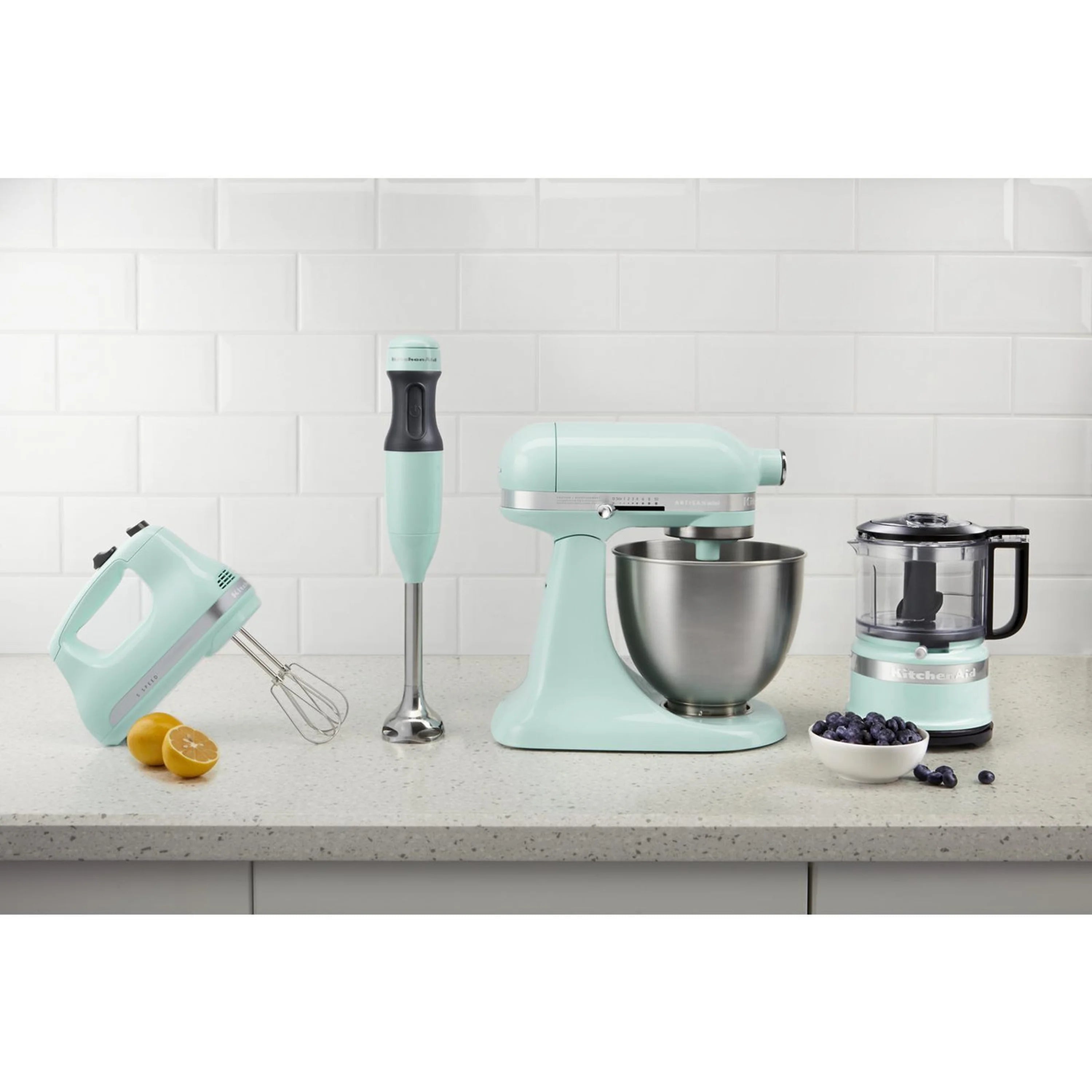 Ice-colored KitchenAid hand mixer, whisk-style beaters, and stand mixer bowl on counter