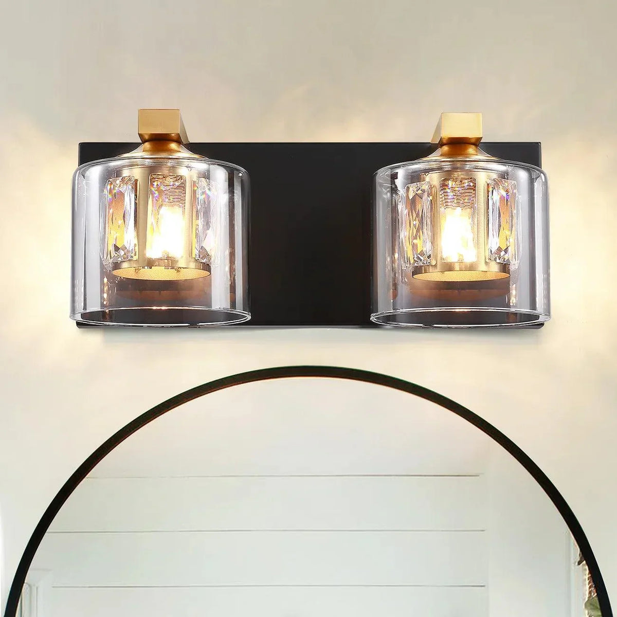 Two-light vanity light with clear glass cylinder shades and dark backplate with gold accents