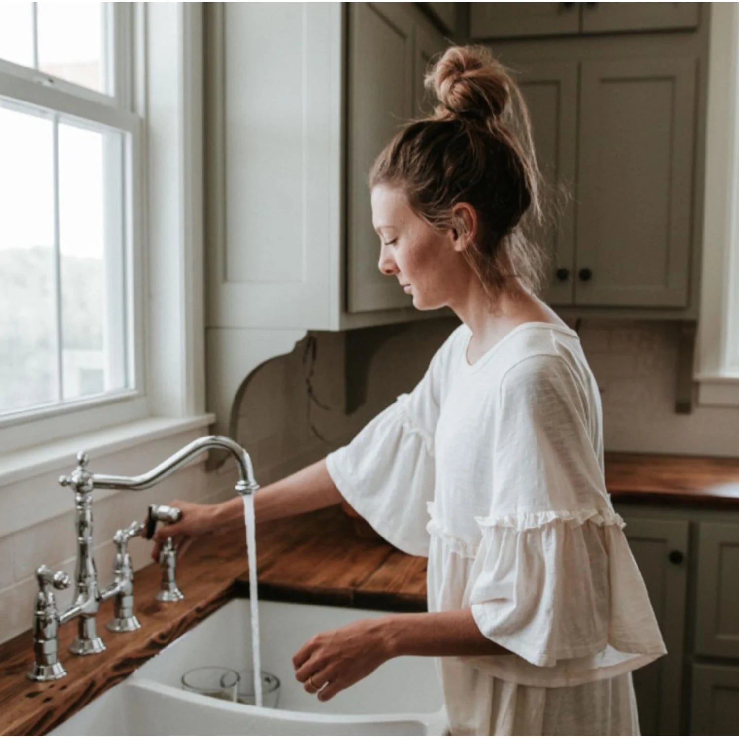 Polished chrome bridge kitchen faucet with pull-down sprayer stream over sink