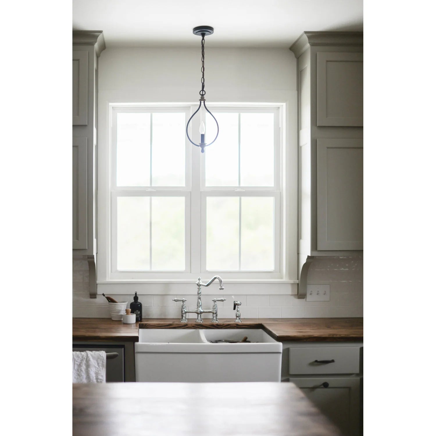Polished chrome bridge kitchen faucet centered on a sink with side sprayer