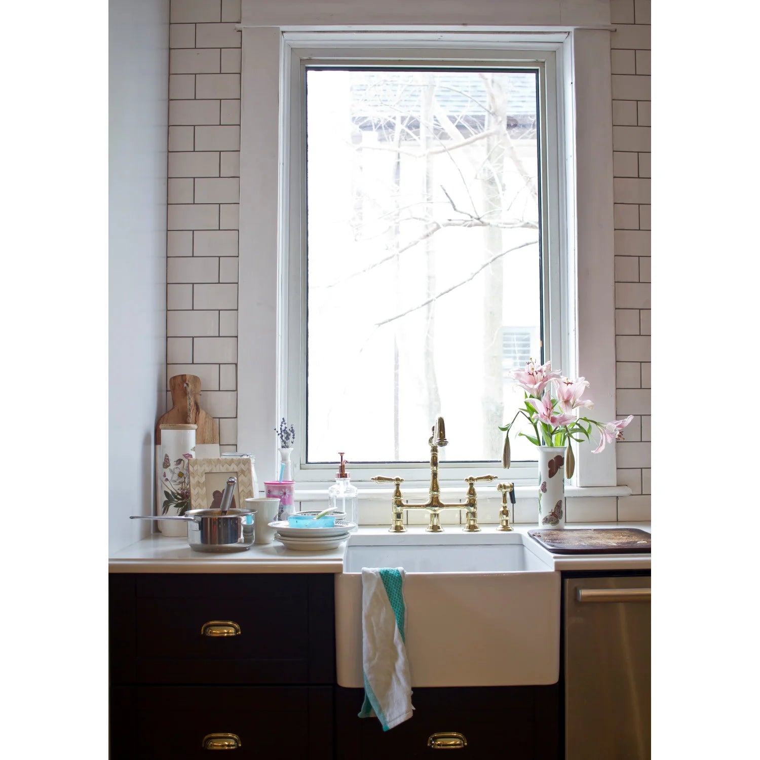 Polished brass bridge kitchen faucet with dual handles and side sprayer mounted on sink