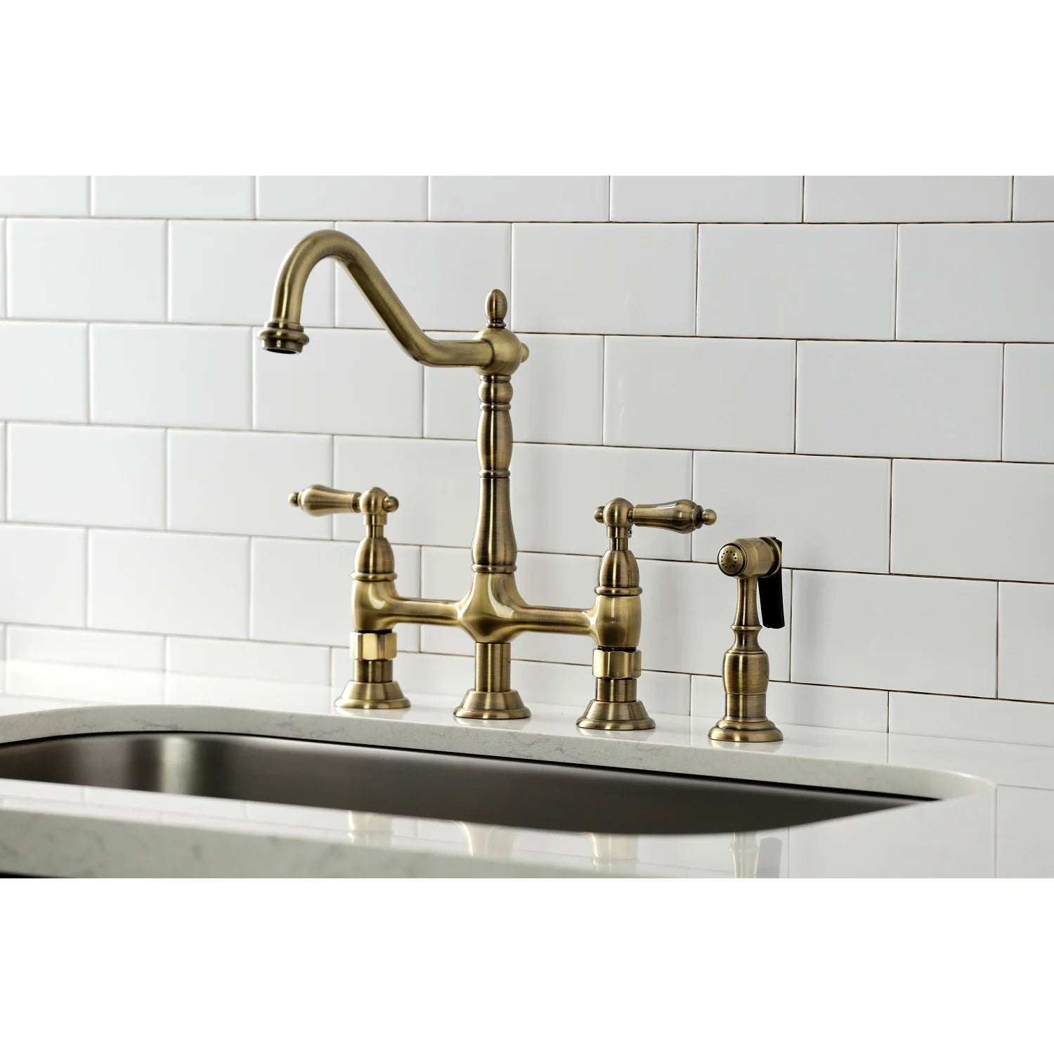Antique brass bridge kitchen faucet with side sprayer over white countertop sink