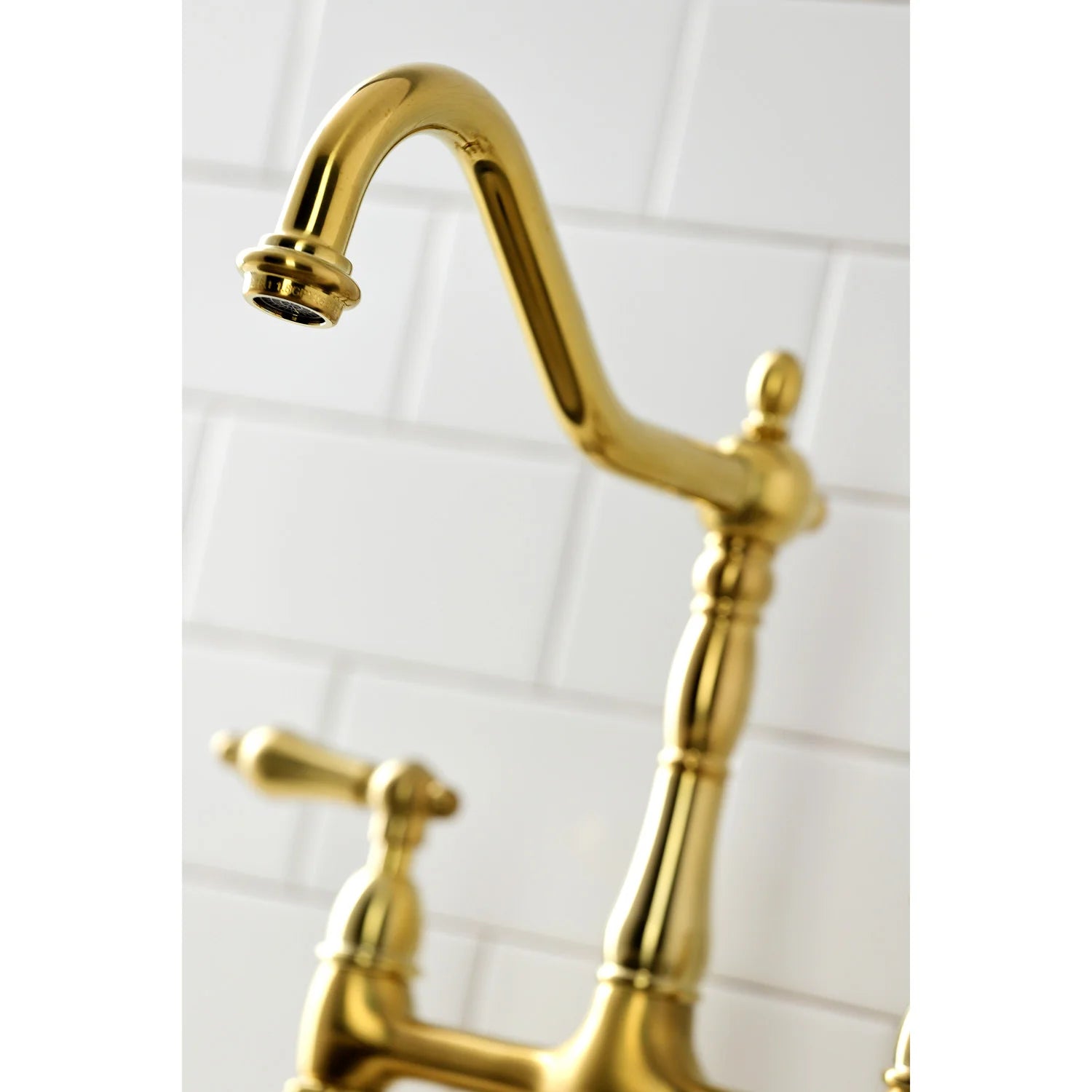Close-up of brushed brass gooseneck faucet spout and handle base