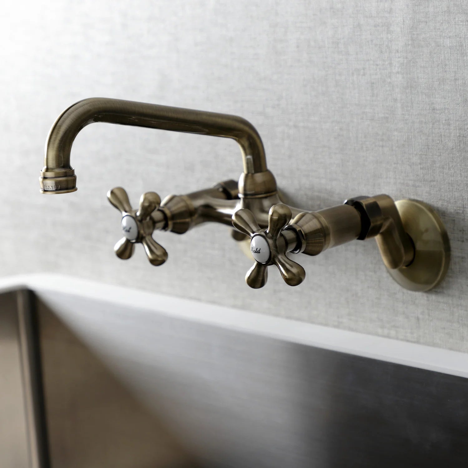 Antique brass double-handle wall-mount faucet with arched spout over sink
