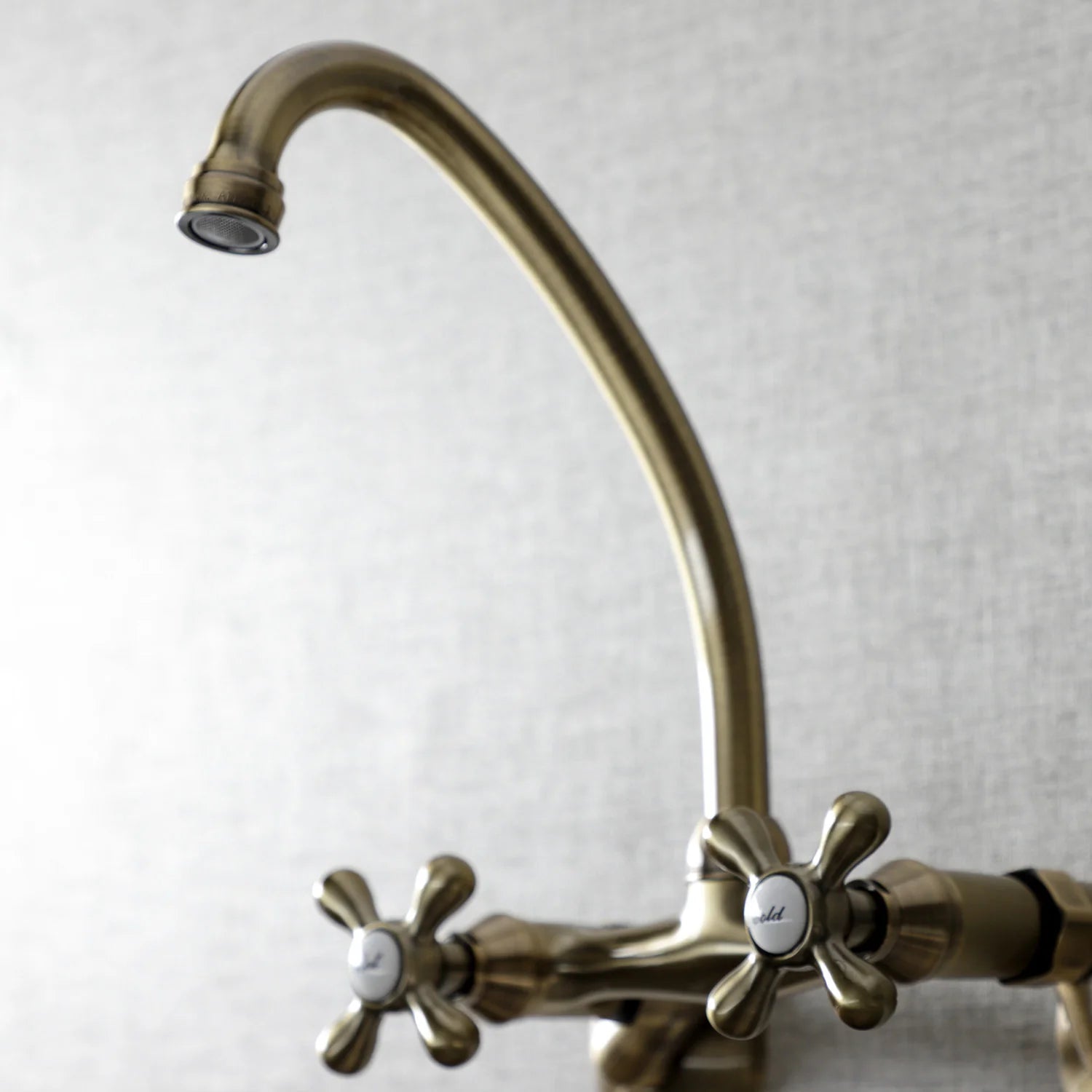 Antique brass wall-mount faucet with curved spout and cross handle