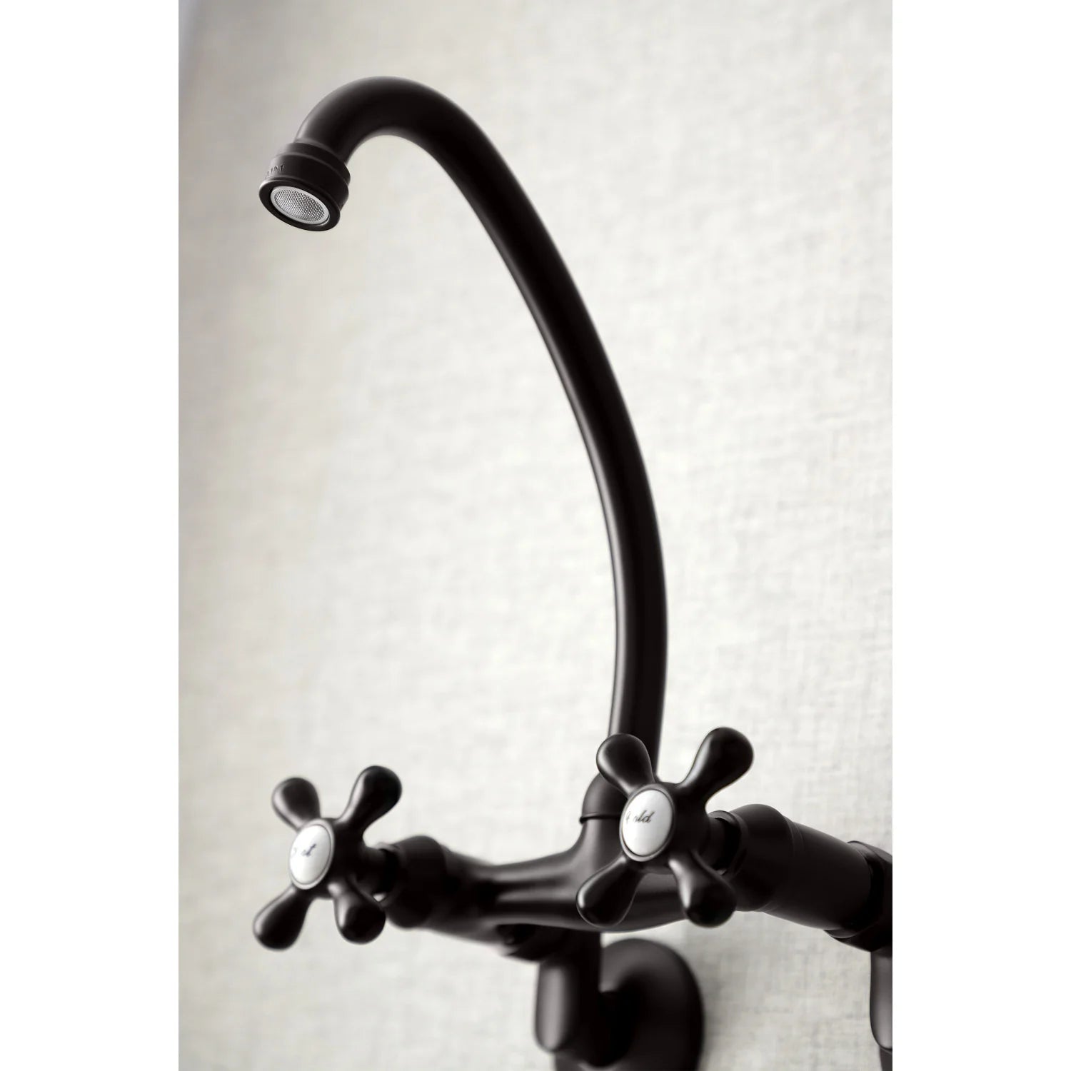 Curved oil-rubbed bronze spout with cross handles on a bridge kitchen faucet