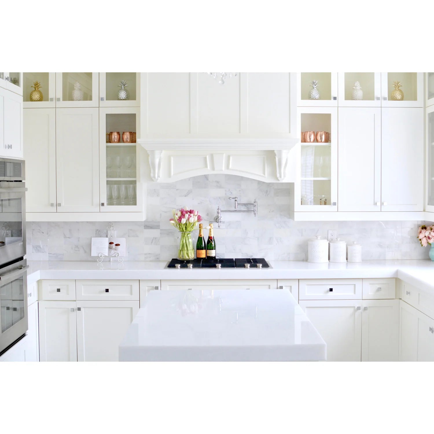 Polished chrome pot filler faucet mounted behind a countertop and stove