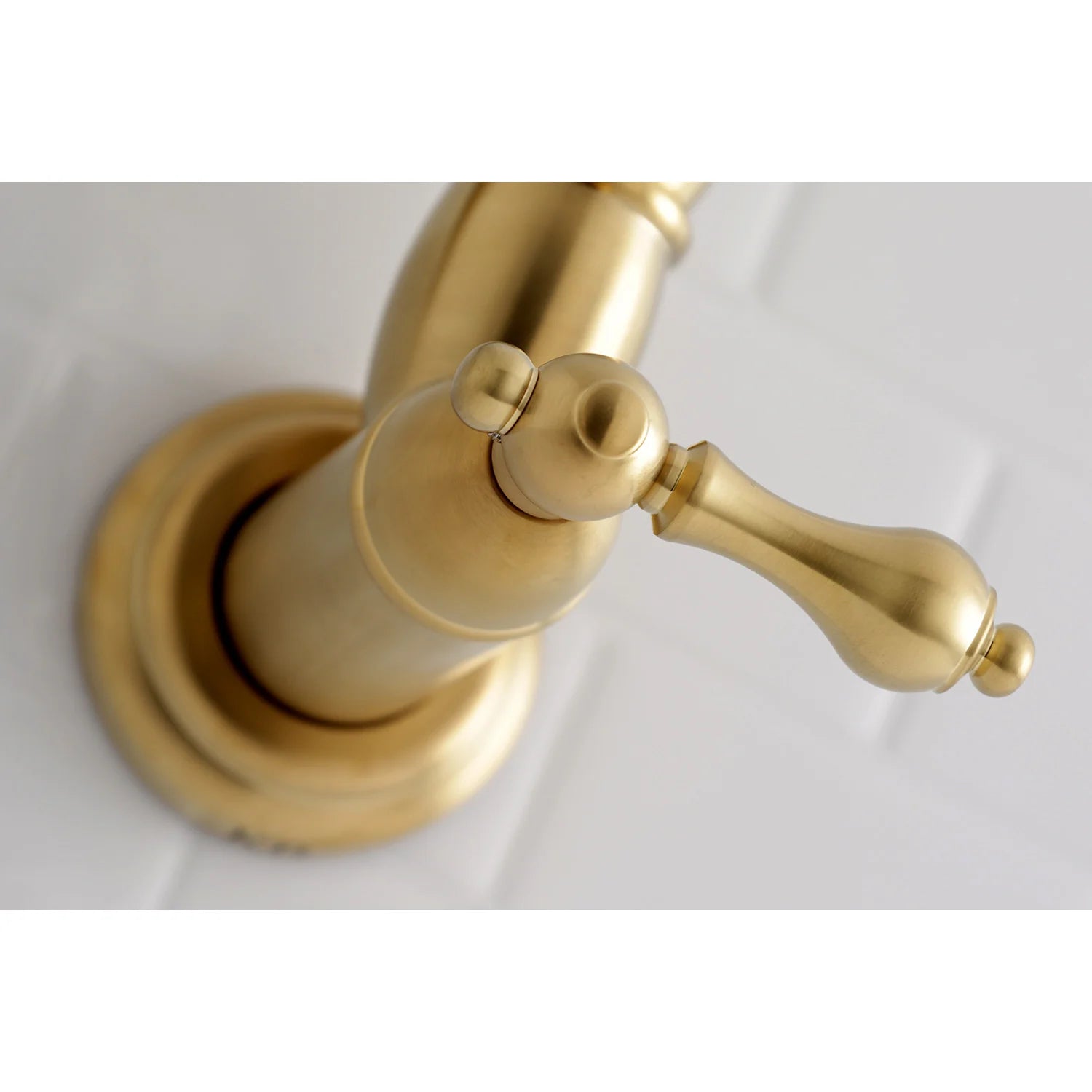 Brushed brass pot filler faucet close-up with curved spout and control handles