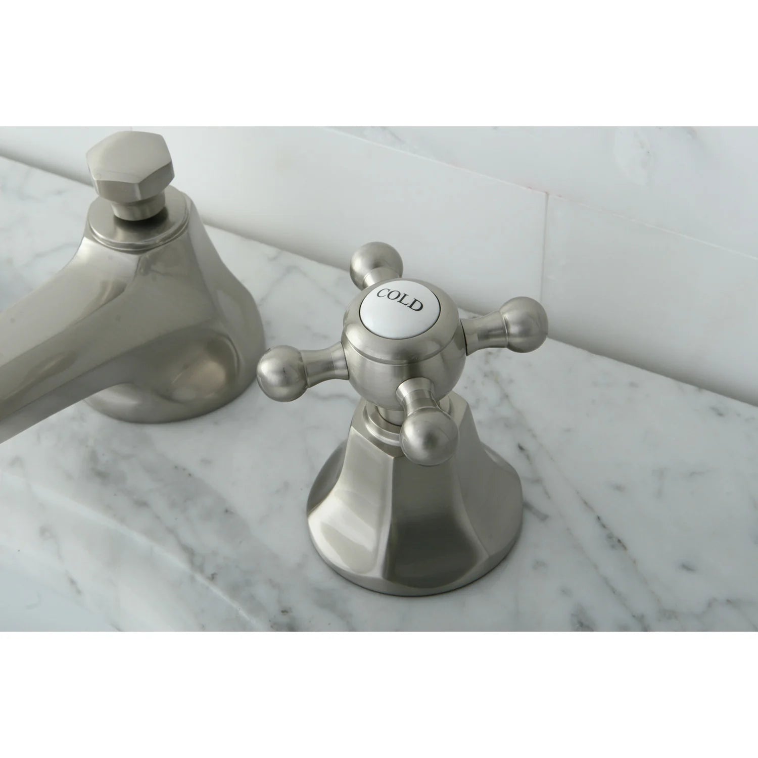 Brushed nickel bathroom faucet with COLD-labeled control cap and cross handle