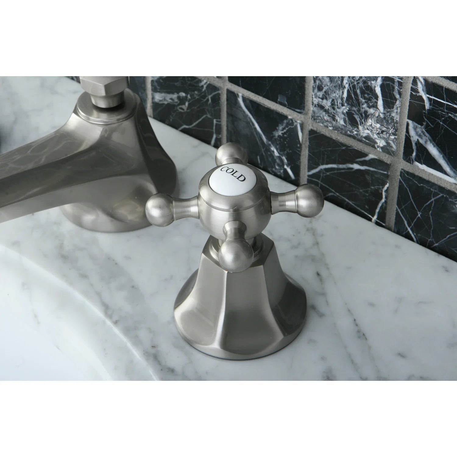 Brushed nickel faucet handles with round caps labeled COLD and spout