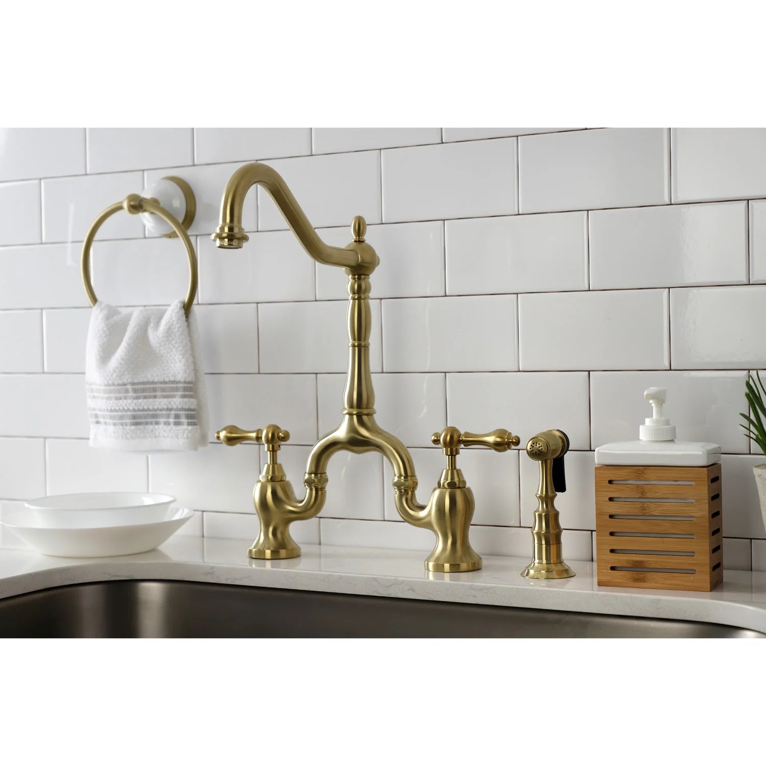 Brushed brass bridge kitchen faucet set with side sprayer on countertop