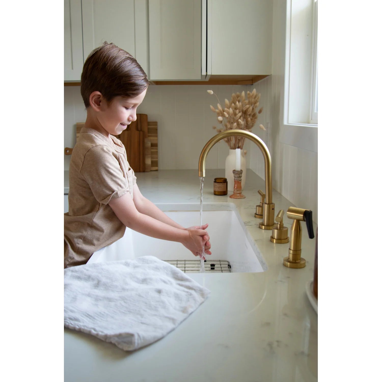 Brushed brass kitchen faucet with two handles and arched spout over white sink