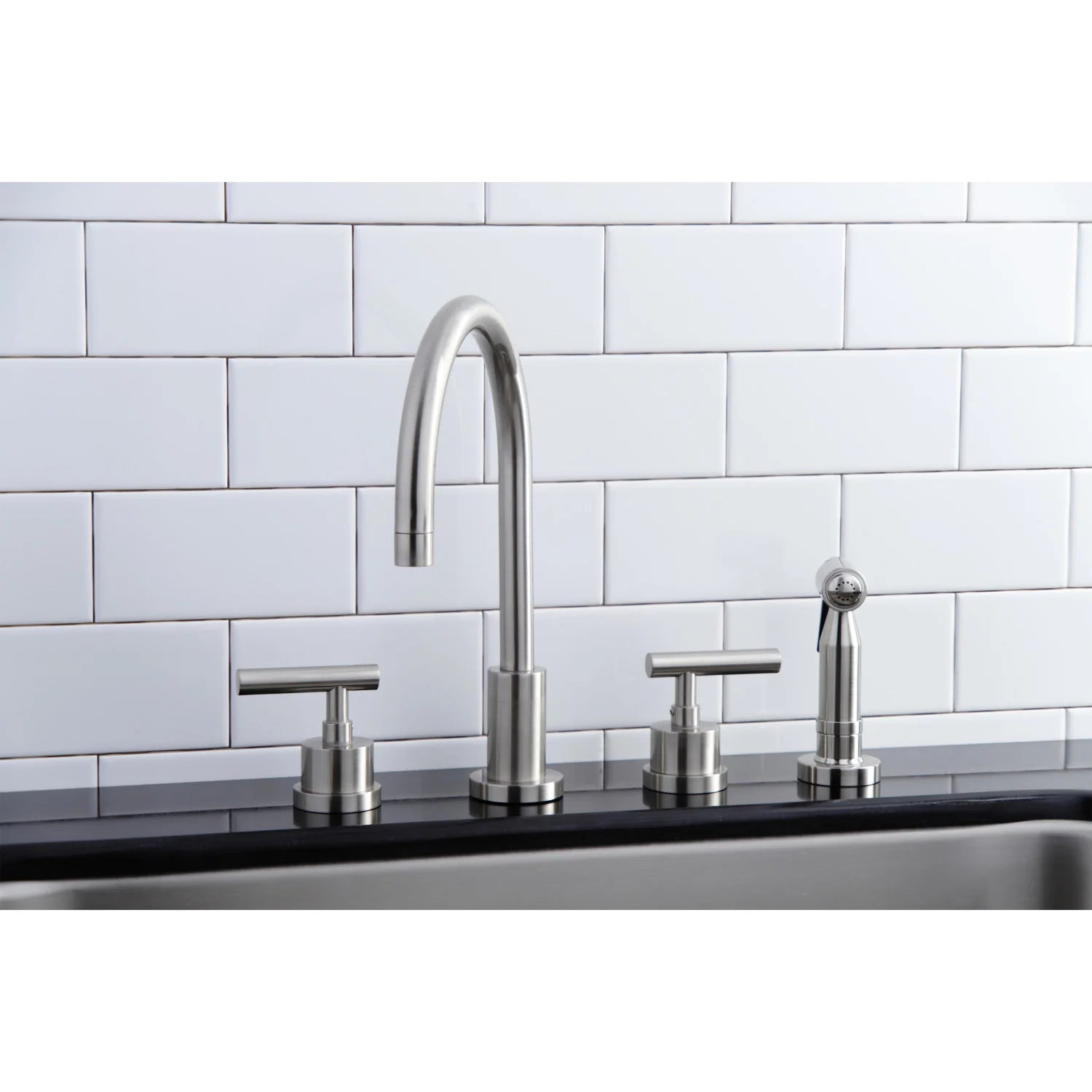 Tall brushed nickel kitchen faucet with two handles and side sprayer on sink