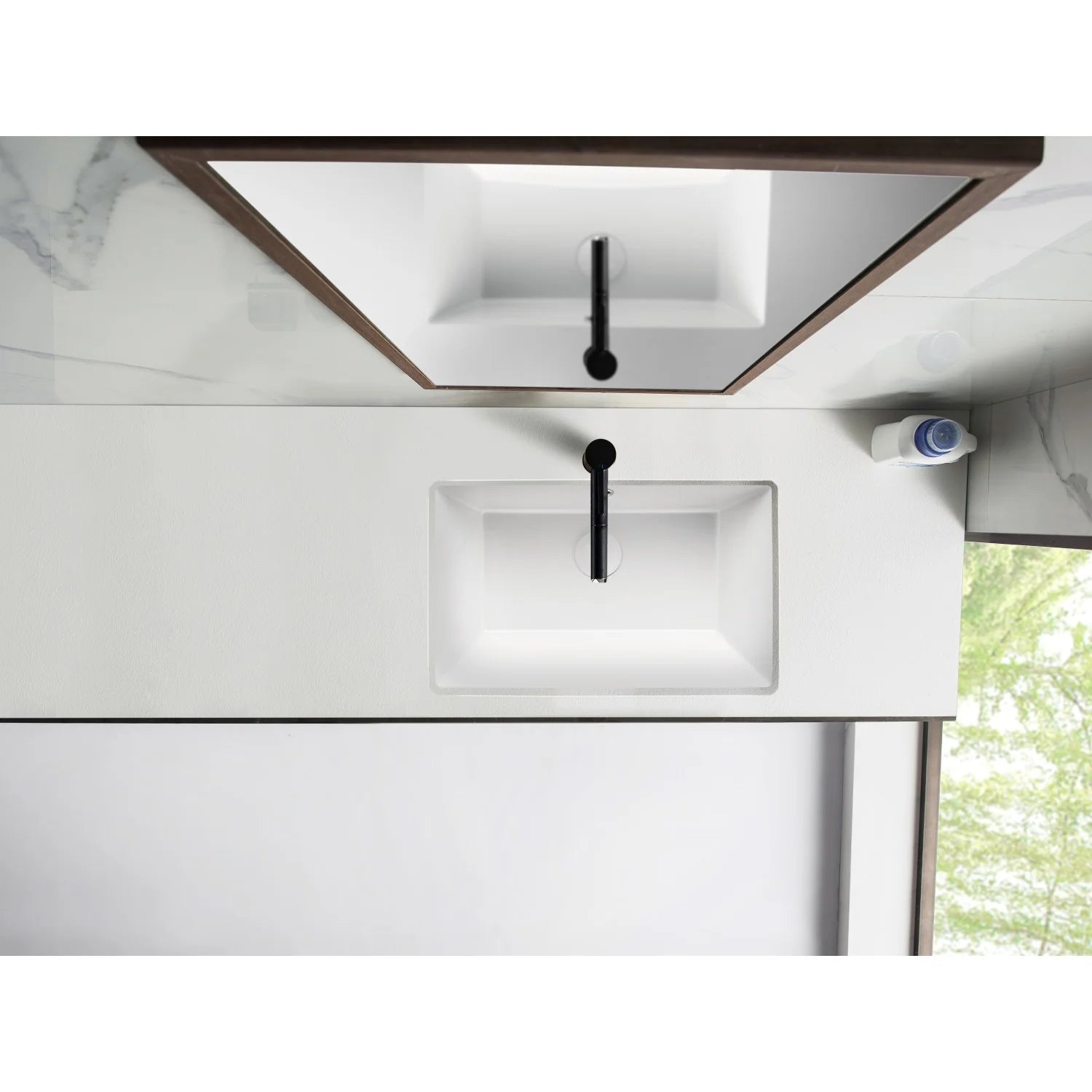 White rectangular undermount bathroom sink installed under a countertop with drain