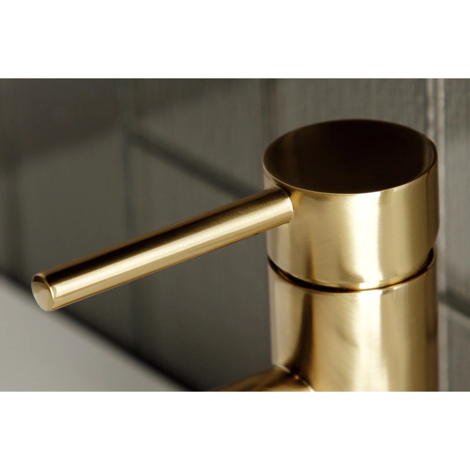 Brushed brass single-handle bathroom faucet close-up of cylindrical handle and outlet