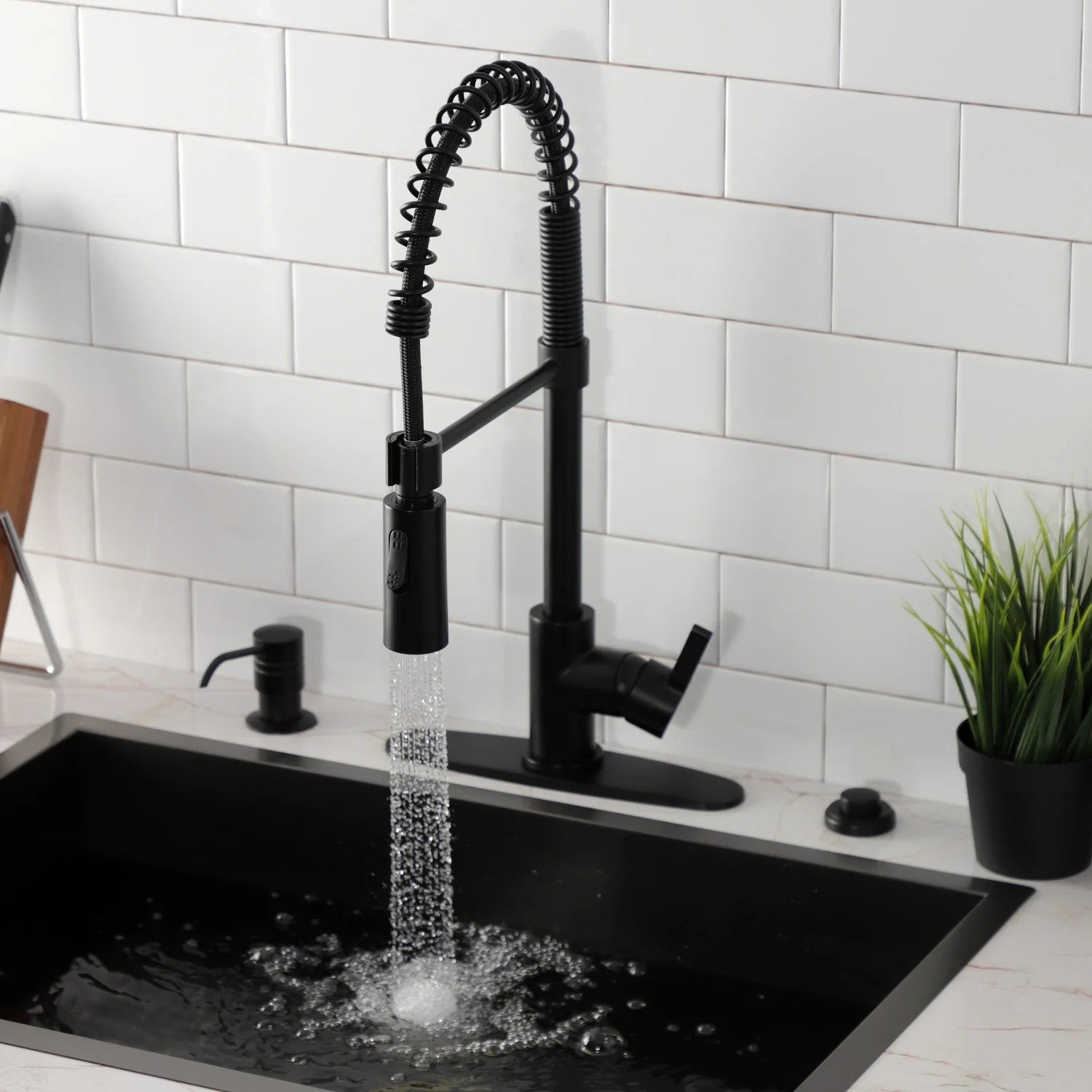 Matte black pre-rinse kitchen faucet dispensing water over a black sink