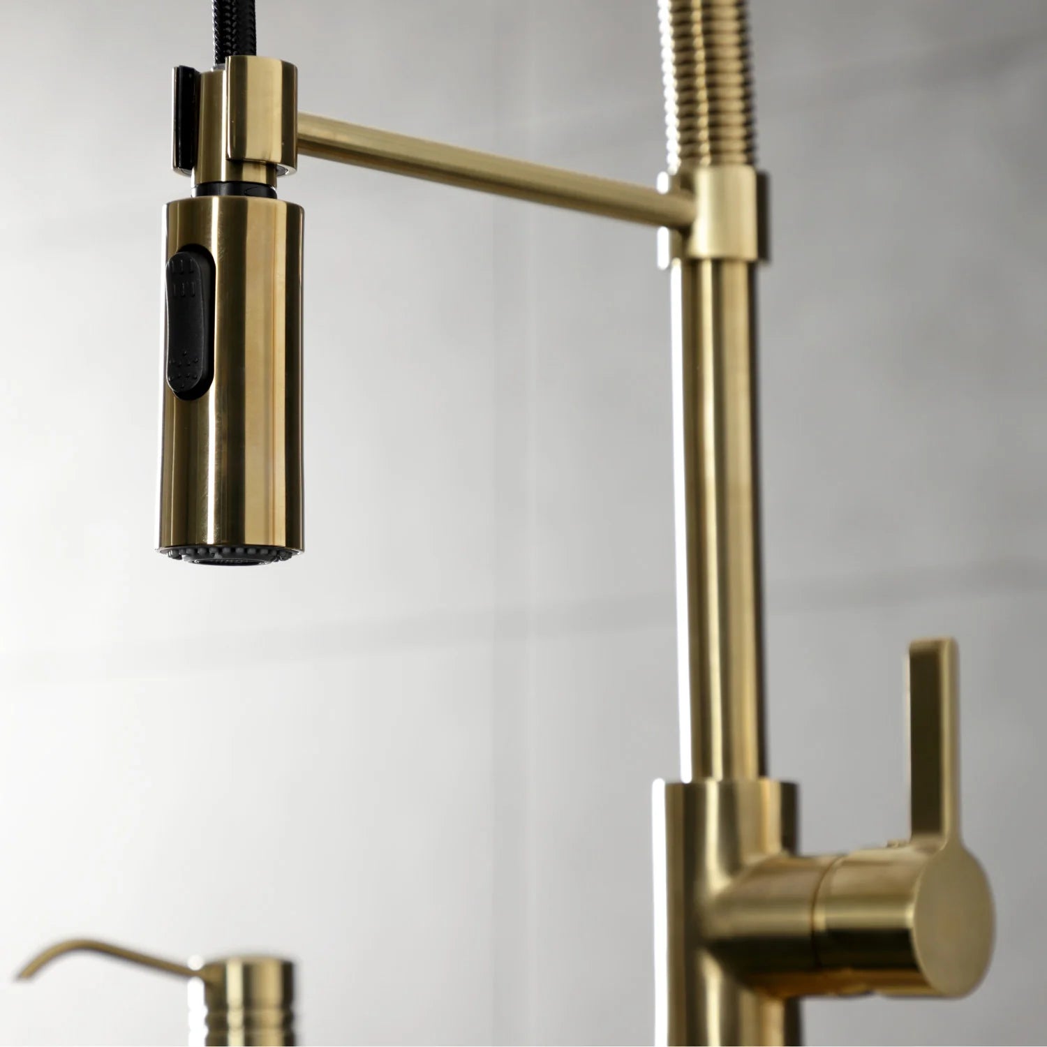 Brushed brass kitchen faucet with single handle, spout, and coiled spray hose