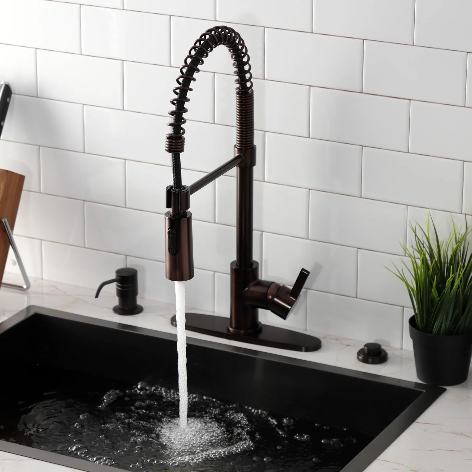 Oil-rubbed bronze deck-mount kitchen faucet with flowing water and coiled spray hose